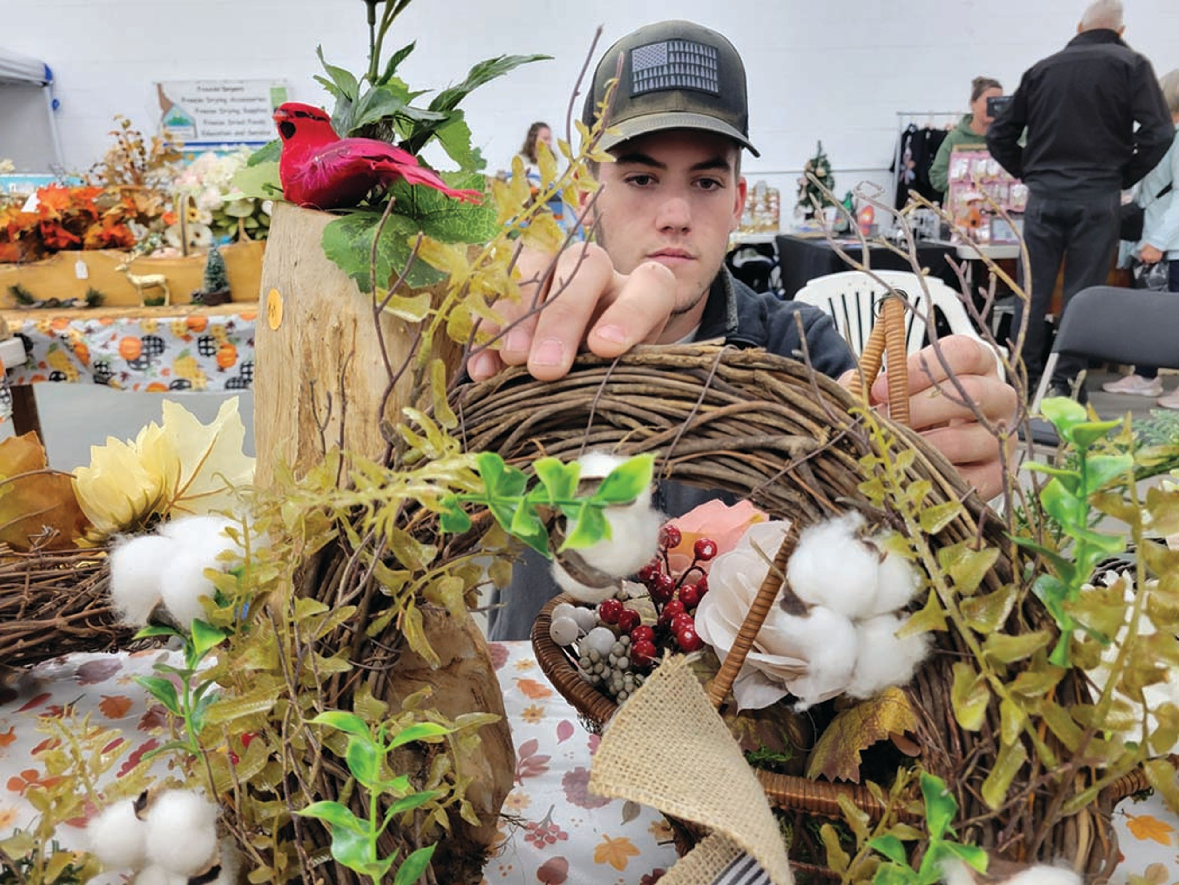 Tyler Perkett adjusts the collection of fall decorations on display as vendors from various communities across Idaho prepare for the Fall Harvest Festival.