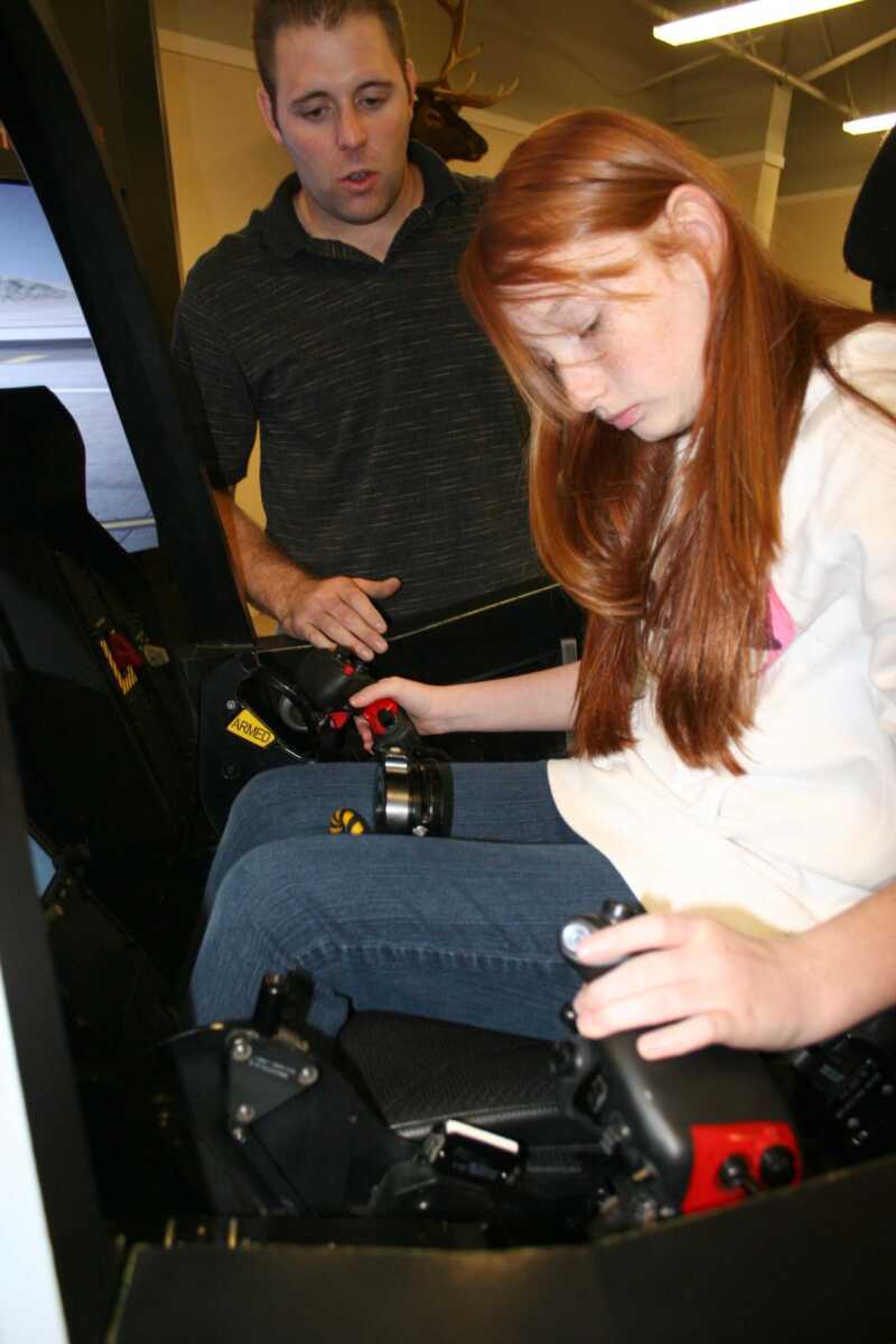 Kyle McGehee points out the features of the F-35 Joint Strike Fighter's throttle controls as Kylee Brooks prepares to fly in the company's jet simulator at the Elk's Lodge on July 14. The 12 year old was one of many local residents who gathered at the lodge for their first look at the next-generation fighter program with many opting to take a spin in the Joint Strike Fighter cockpit simulator. McGehee serves with Lockheed Martin's office in Fort Worth, Texas. <i><small>Photo by Brian S. Orban</i></small>
