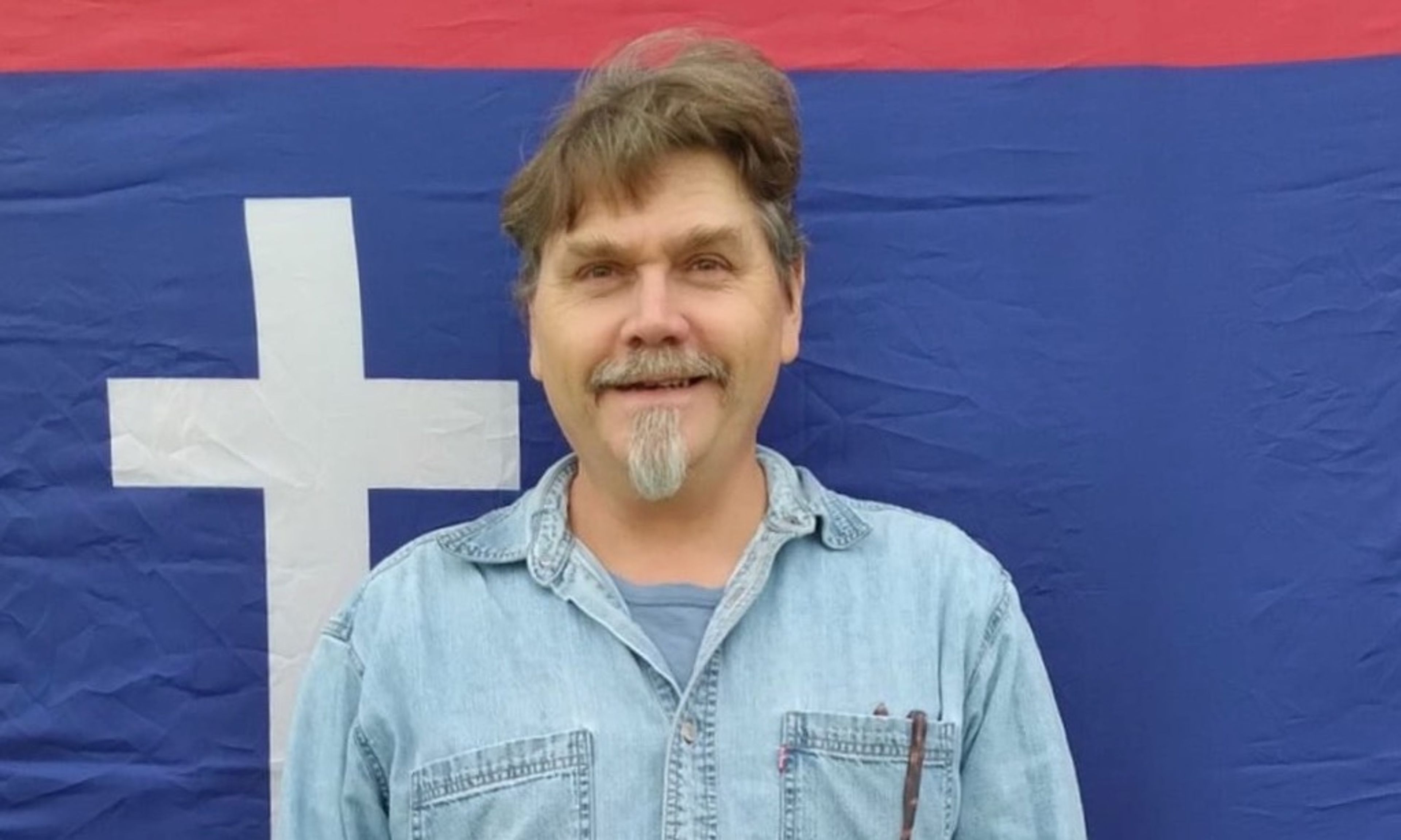 Darrell McClanahan of Milo, a candidate for governor who the Missouri Republican Party attempted to remove from the ballot for being an ‘honorary’ KKK member. He is shown in a photo from his 2022 campaign for U.S. Senate, standing in front of the flag of the Missouri State Guard, a military force formed in 1861 to oppose the Union in the Civil War.