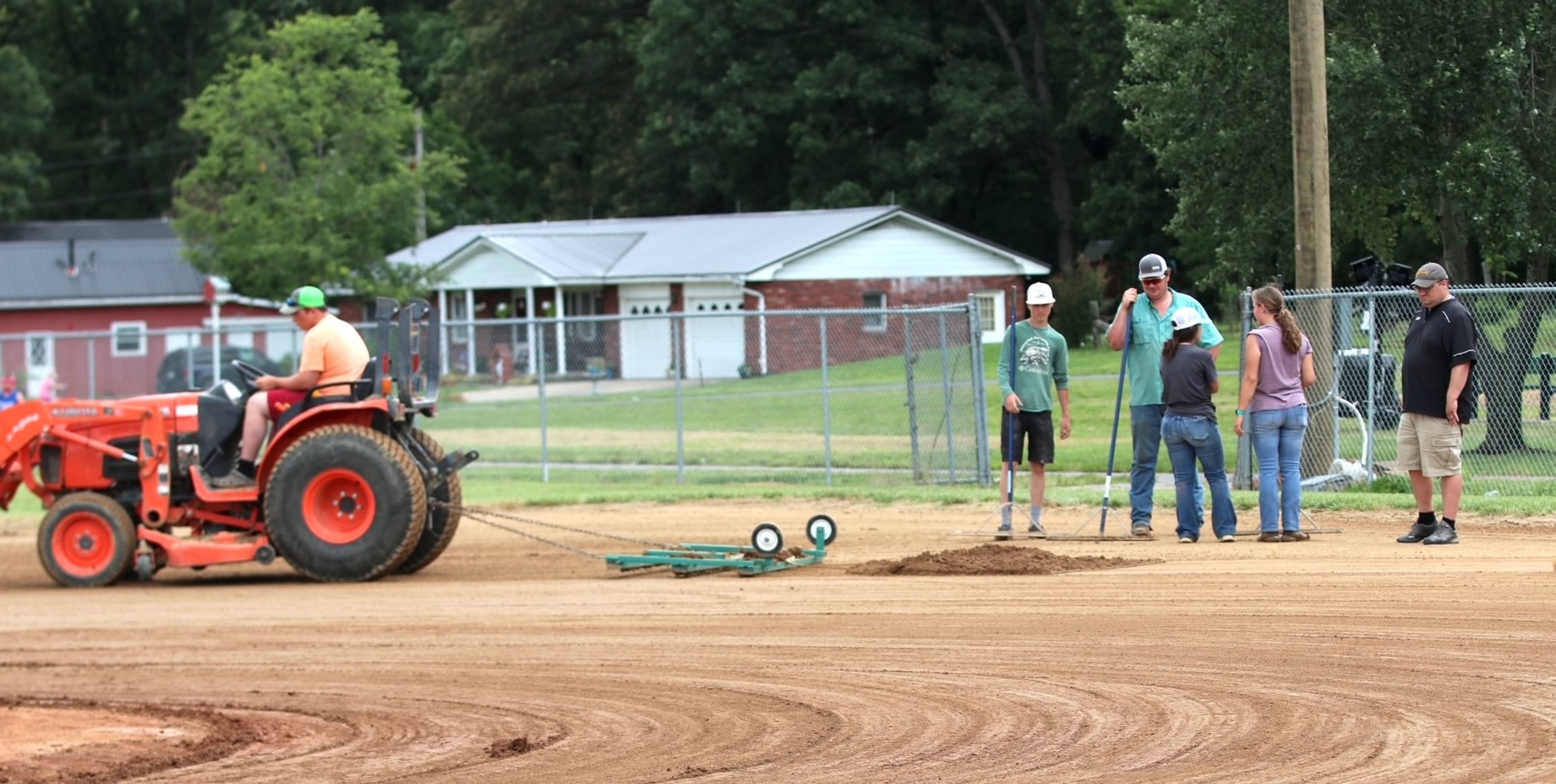 
High school volunteers Garrett Brown, Ava Jansen, Fayelinn Brown, Jacob Cureton and Shane Jansen prep the field after early morning rain showers Saturday. Alan Beussink checks the progress to determine the field readiness for the next game.