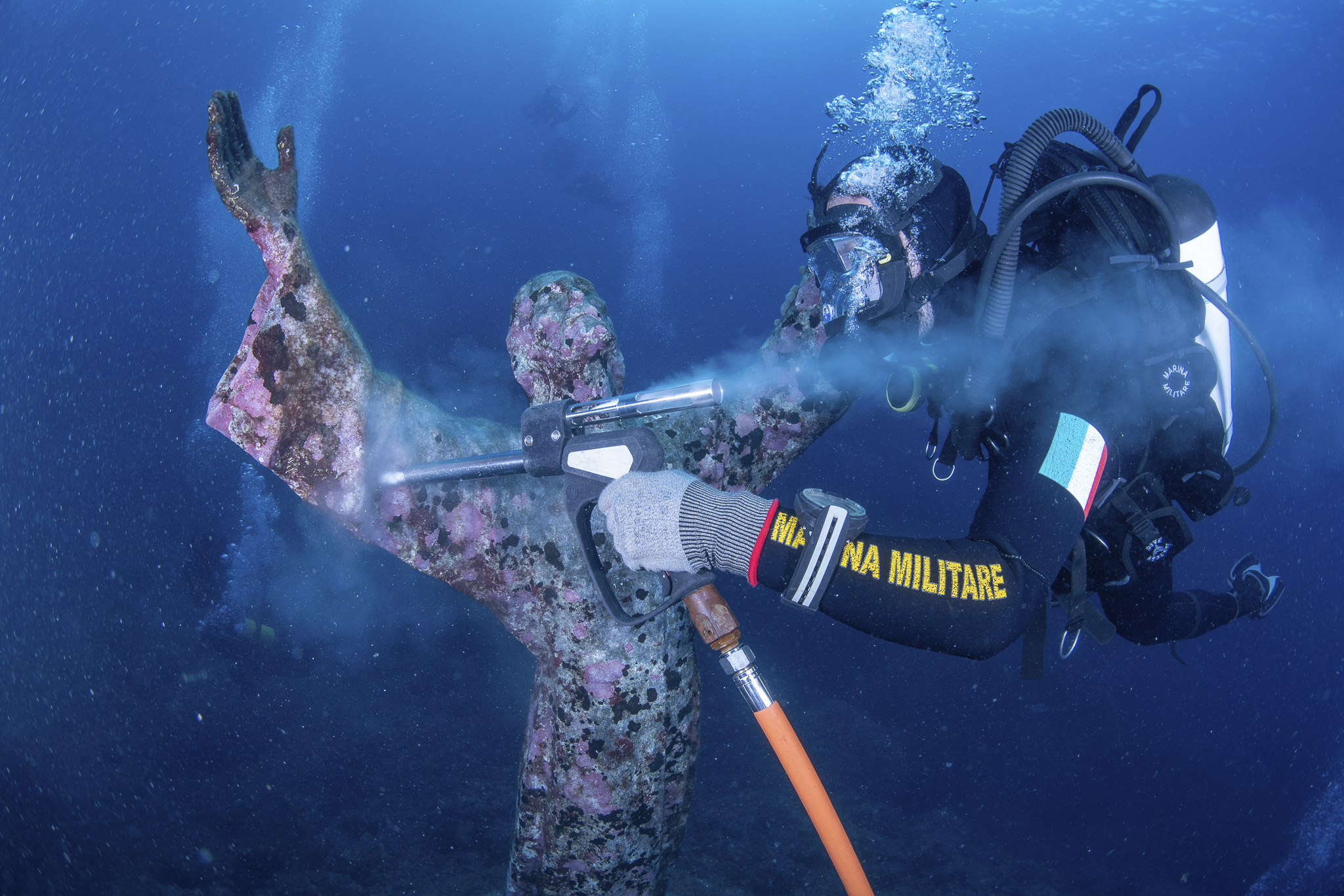 Italian divers water-blast the popular underwater statue of