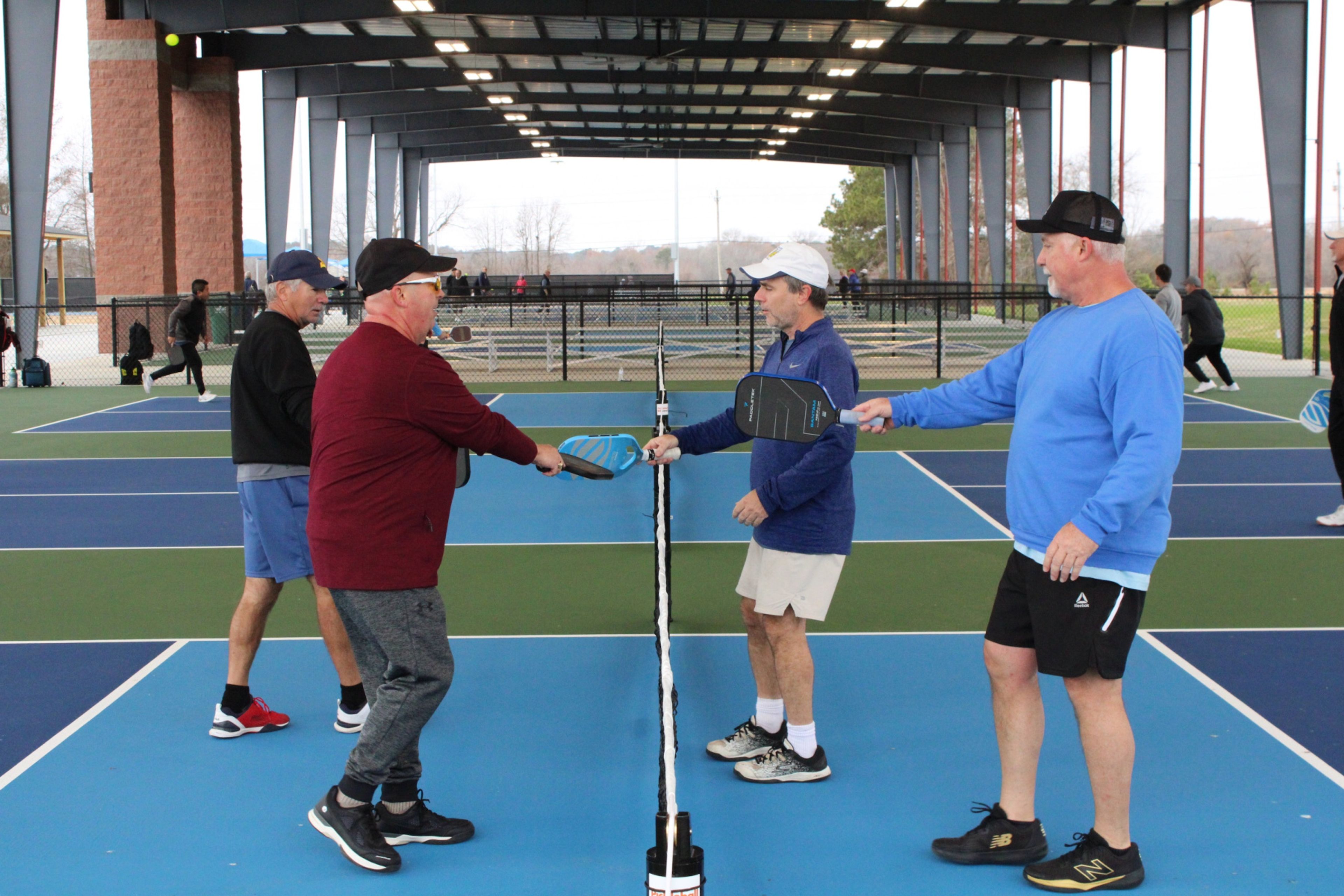 Pickleball players Jeff Batchelor, Trip Rodgers, Jobe Makar and Carlos Tyndall touch paddles after a game at the new pickleball facility at J. Burt Gillette Athletic Complex on Monday. Drew C. Wilson | Times
