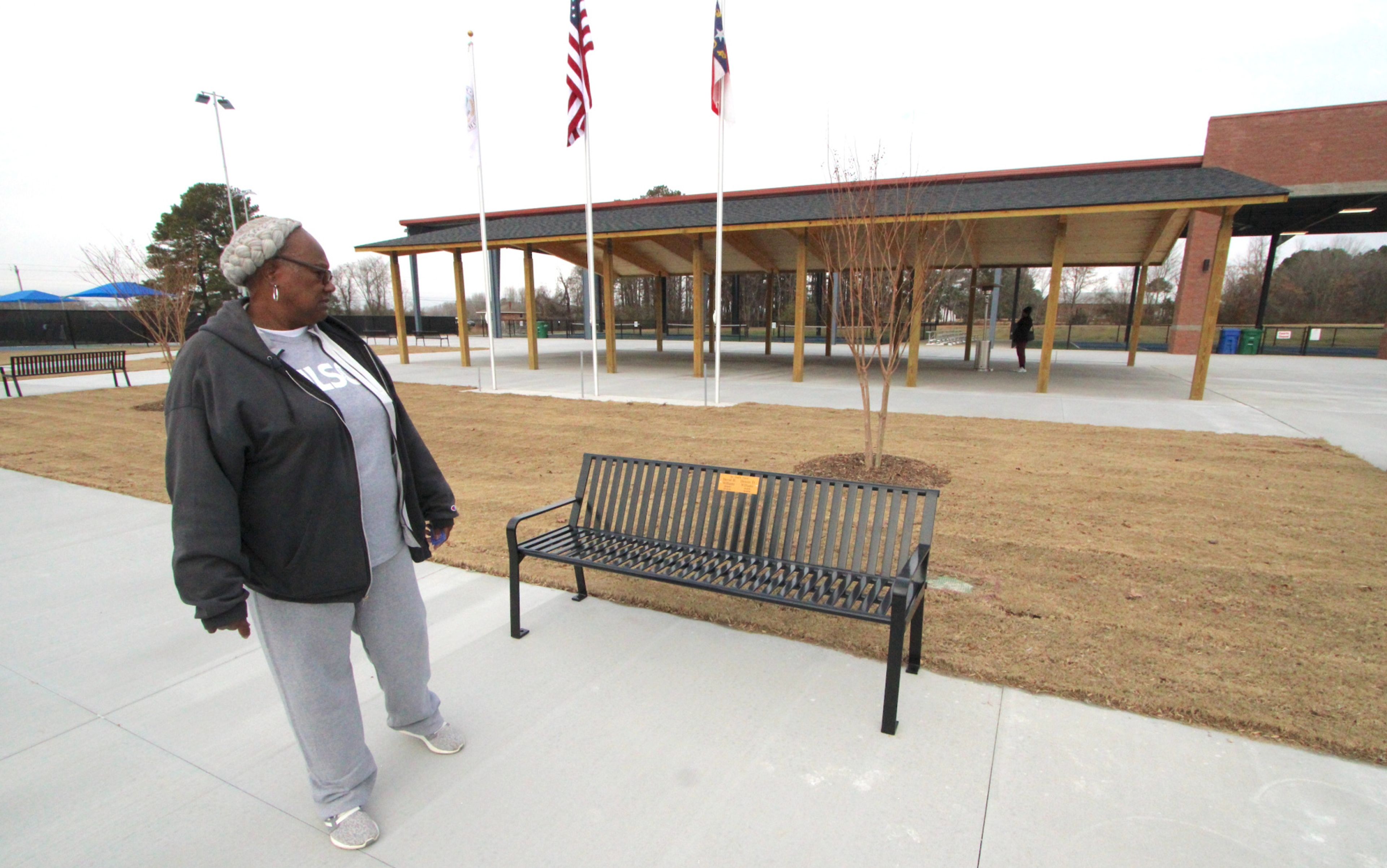 Patricia Williams stands by a bench purchased in honor of her late sons, David H. Williams and Dennis D. Williams, whose names are on a plaque on the bench at the new pickleball facility at J. Burt Gillette Athletic Complex. Drew C. Wilson | Times
