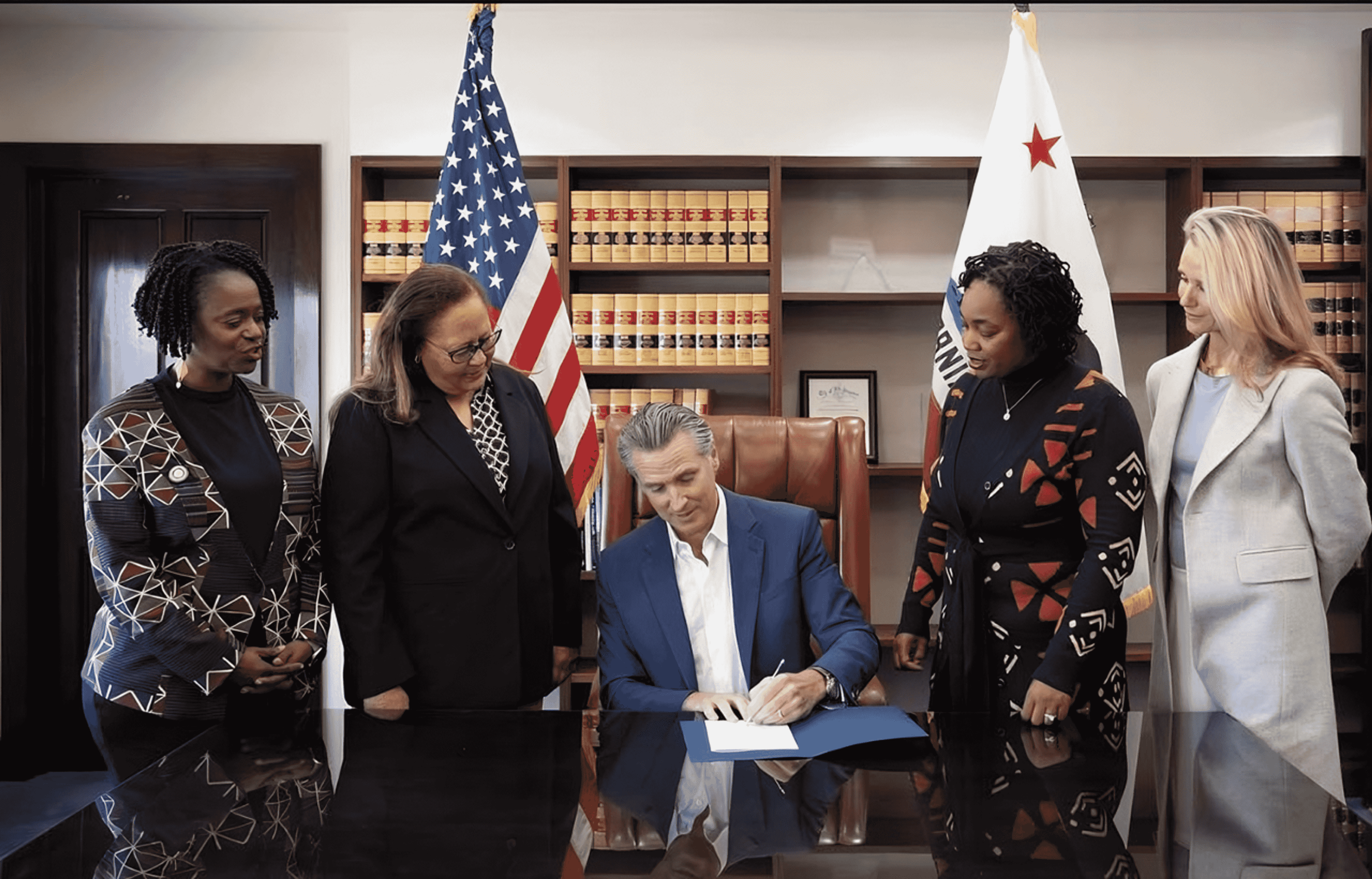 Gov. Gavin Newsom, seated, signs SB 518 as members of the California Legislative Black Caucus look on. The landmark reparative justice bill establishes the Bureau for Descendants of American Slavery, marking the beginning of a process to advance reparative justice for descendants of enslaved people in California. Pictured with Newsom are CLBC members State Sens. Lola Smallwood-Cuevas (D-Los Angeles), far left; Laura Richardson (D-San Pedro), second from left; Akilah Weber Pierson (D-San Diego), second from right; and First Partner Jennifer Siebel Newsom, far right. SB 518 was authored by Weber Pierson. Photo courtesy of the Office of Gov. Gavin Newsom.