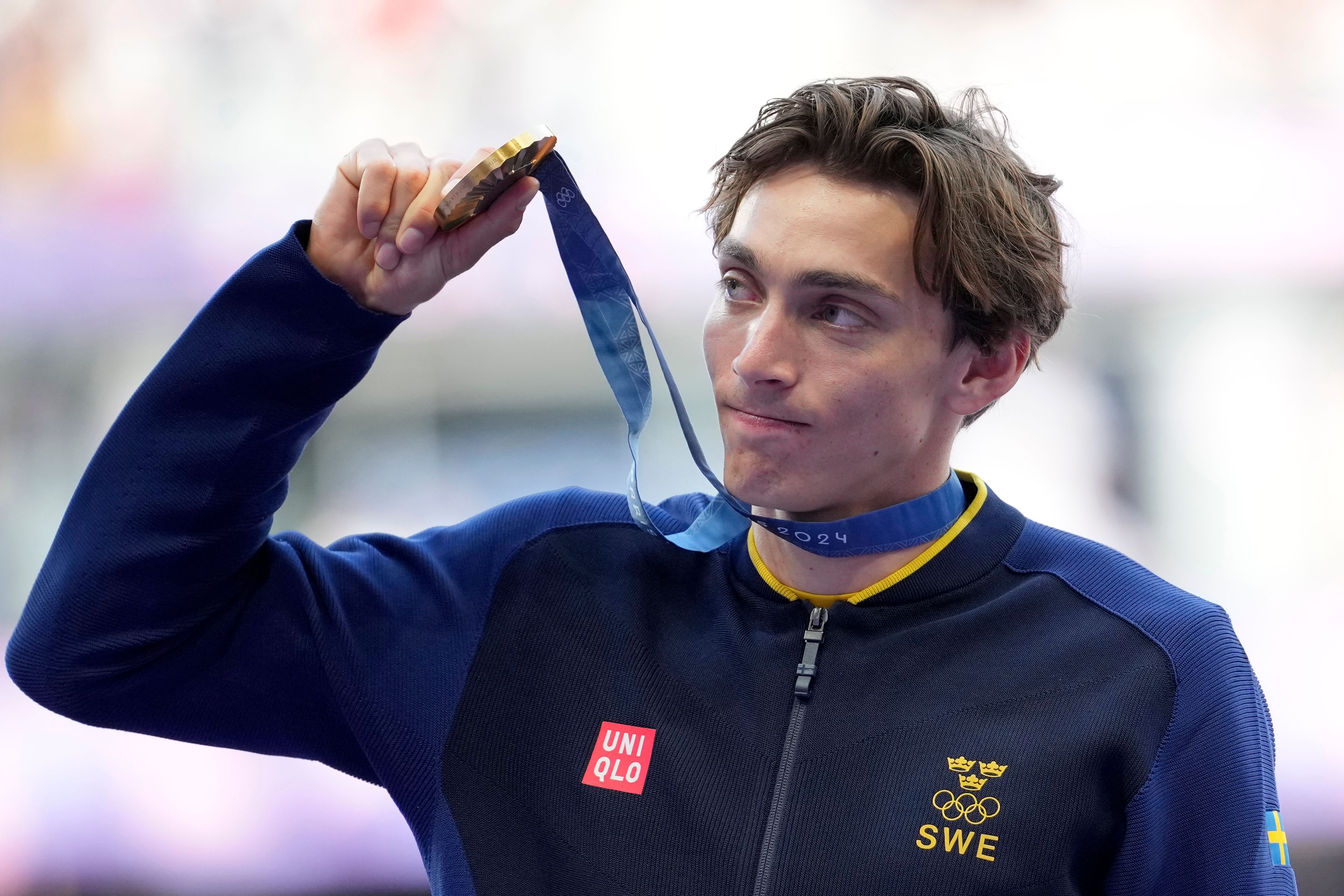 FILE - Armand Duplantis, of Sweden, holds up his gold medal while standing on the podium after winning the men's pole vault at the 2024 Summer Olympics, Tuesday, Aug. 6, 2024, in Saint-Denis, France. (AP Photo/Martin Meissner, File)