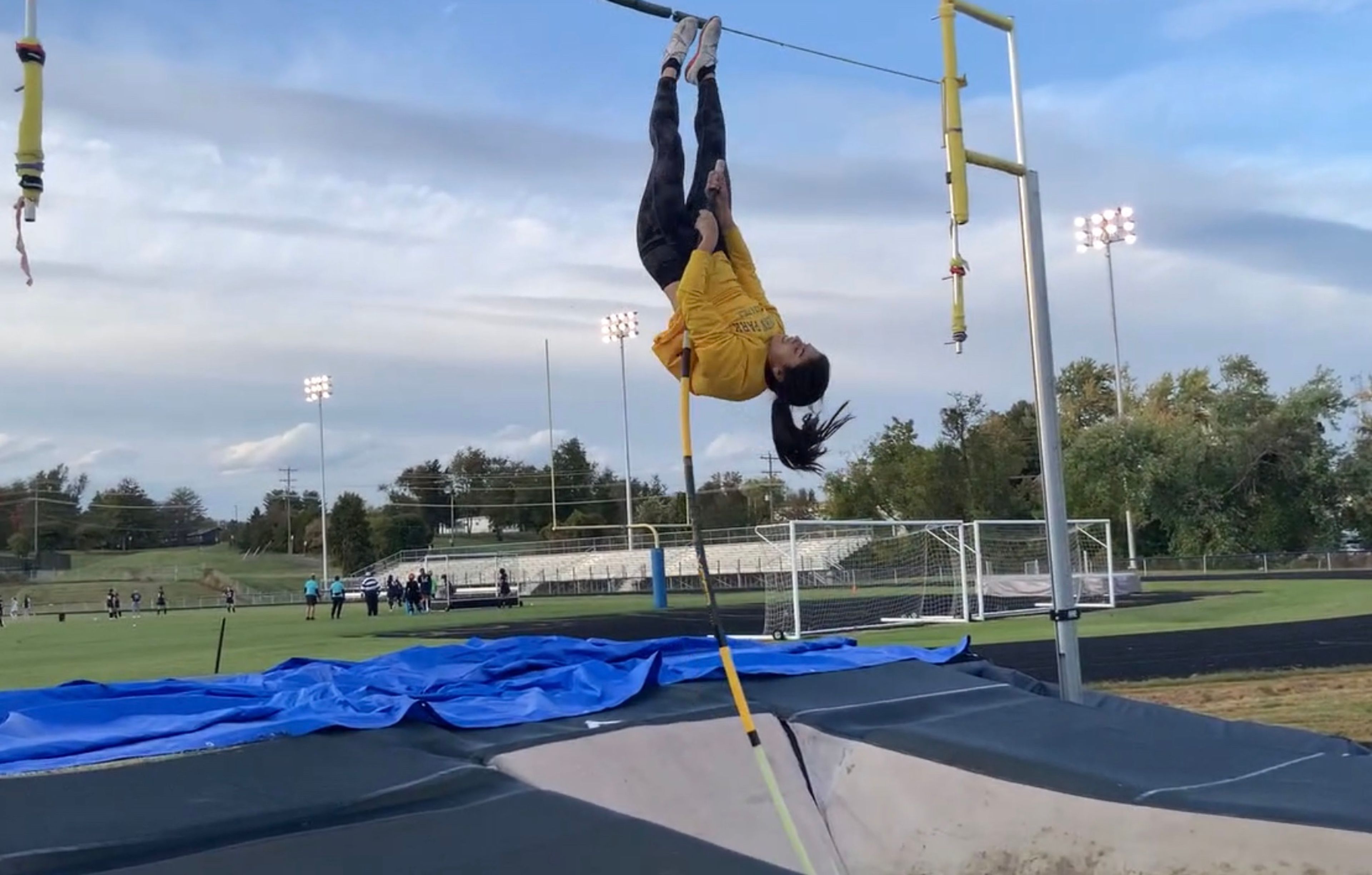 When a pole vaulter rolls the pole past vertical while it is still bent, it can cause them to land too deep in the pit, which is a sign that they are not fully converting their horizontal speed into vertical lift. This situation typically happens when the vaulter’s grip height is too low for their speed and power, allowing the pole to continue bending and rotating even after it has passed vertical. To correct this and bring the landing spot closer to the ideal position, the vaulter can raise their grip, which will reduce the depth of the landing by optimizing the pole's energy release and improving the timing of the vault's peak height​.