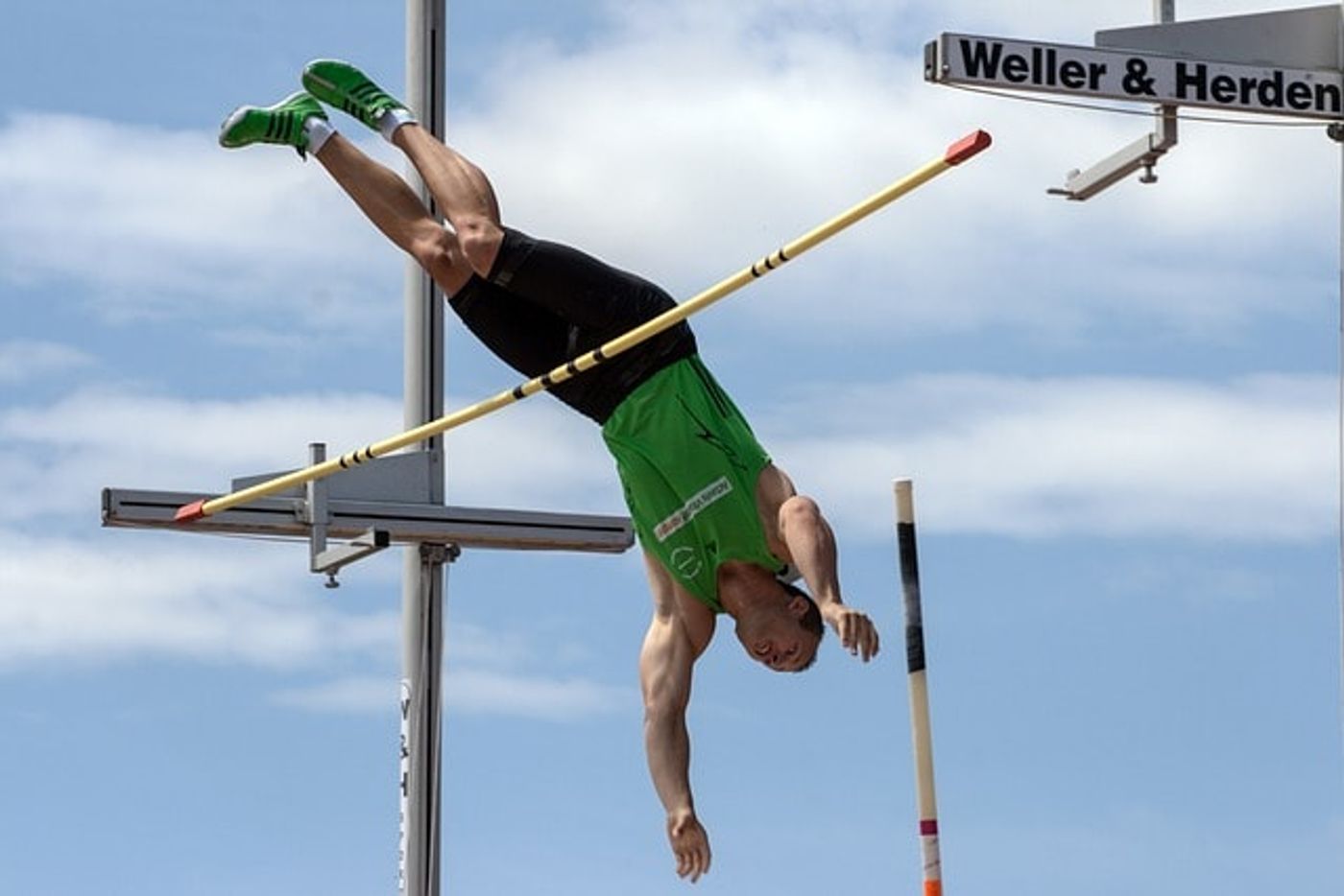 A pole vaulter using modern equipment to fly over the bar. 