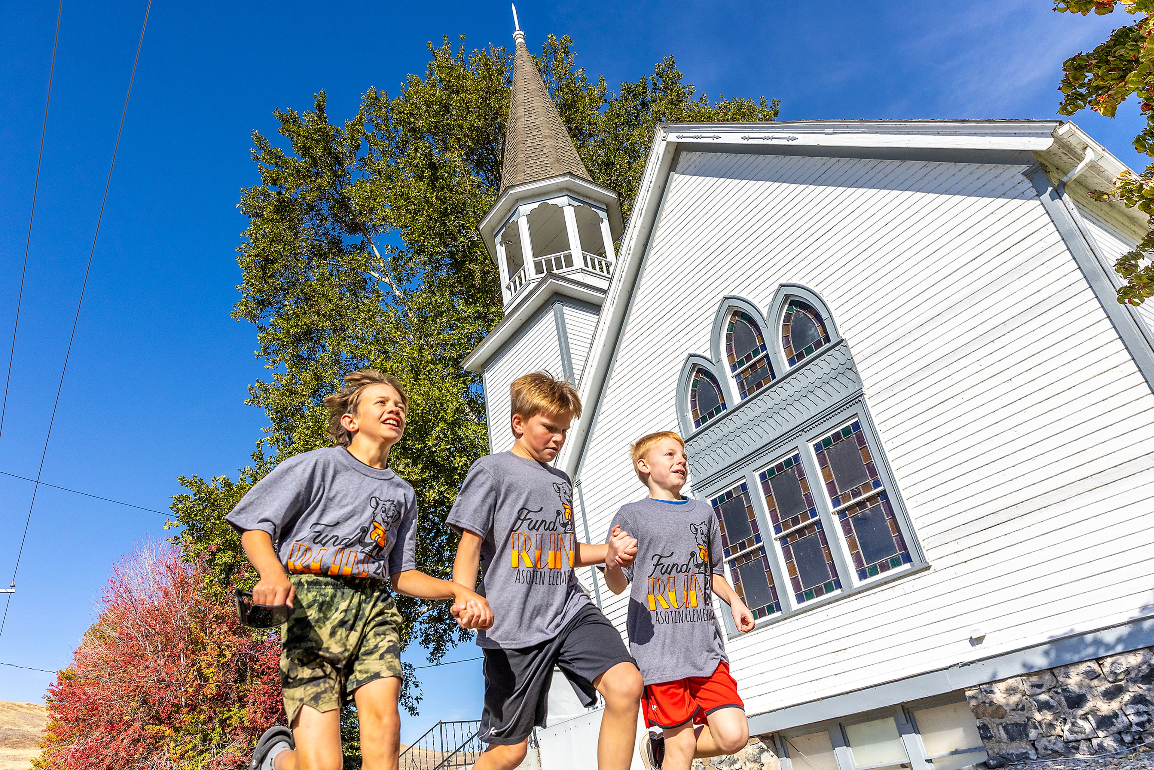 Kids hold hands Thursday as they pass the Asotin Community Center while running laps for the Asotin Fund Run.