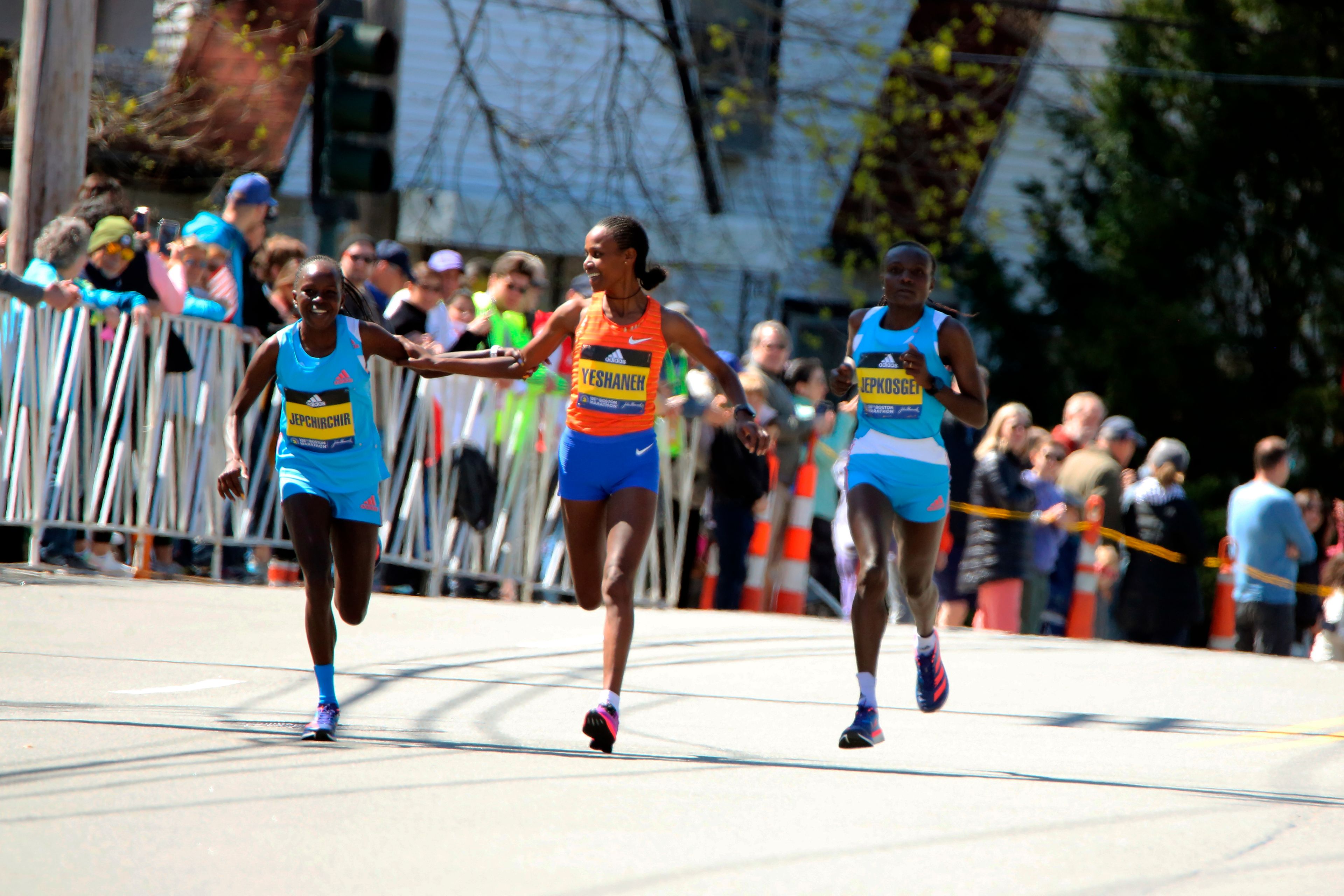 Peres Jepchirchir, of Kenya, left, and Ababel Yeshaneh, of Ethiopia, clasp each others’ arms during the 126th Boston Marathon on Monday in Newton, Mass. Jepchirchir won the women’s division and Yeshaneh finished second. At right is Joyciline Jeopkosgei, of Kenya.