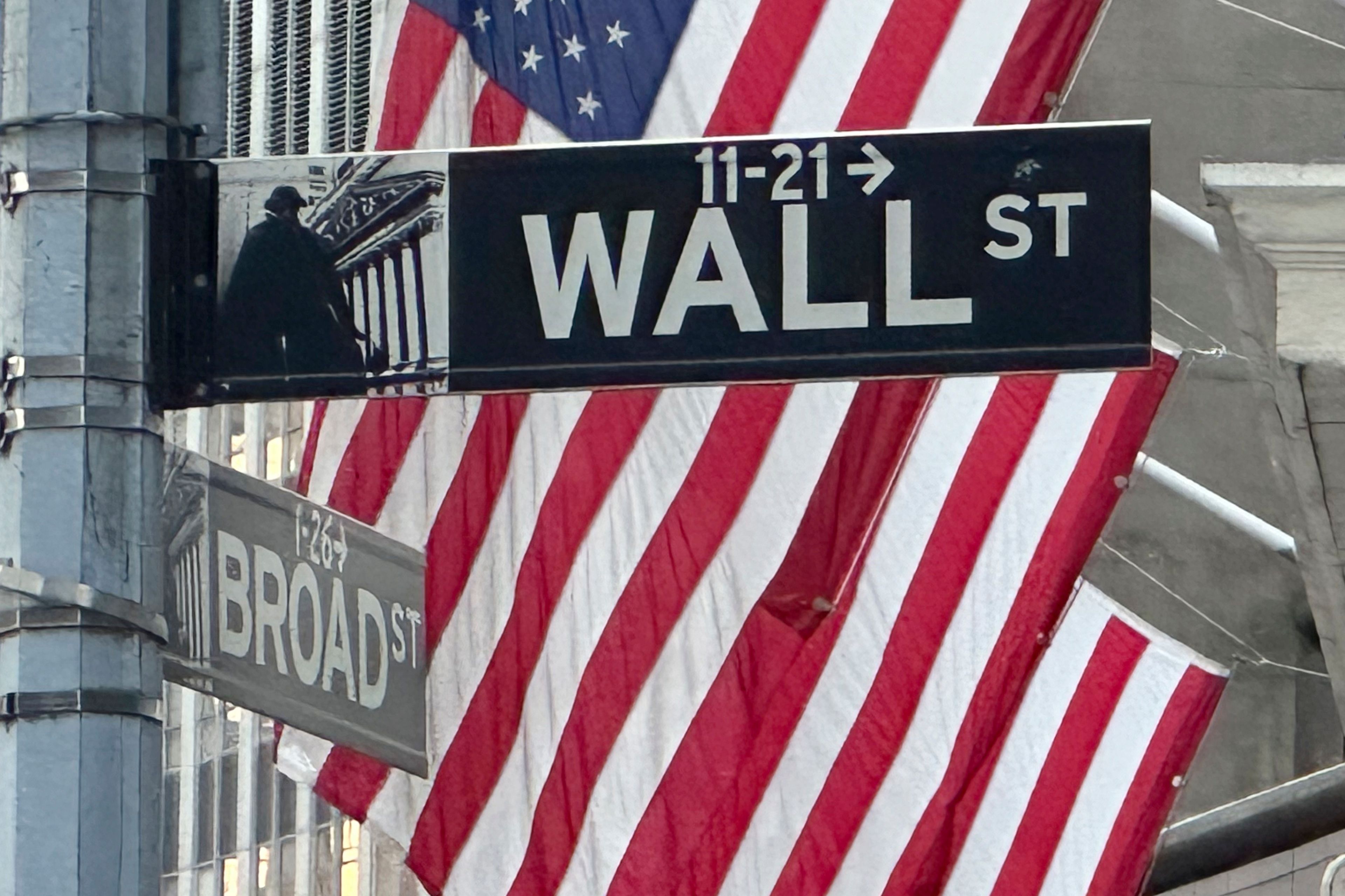 FILE - Signs at the intersection of Broad and Wall Streets stand near flags flying from the New York Stock Exchange on Sept. 4, 2024, in New York.