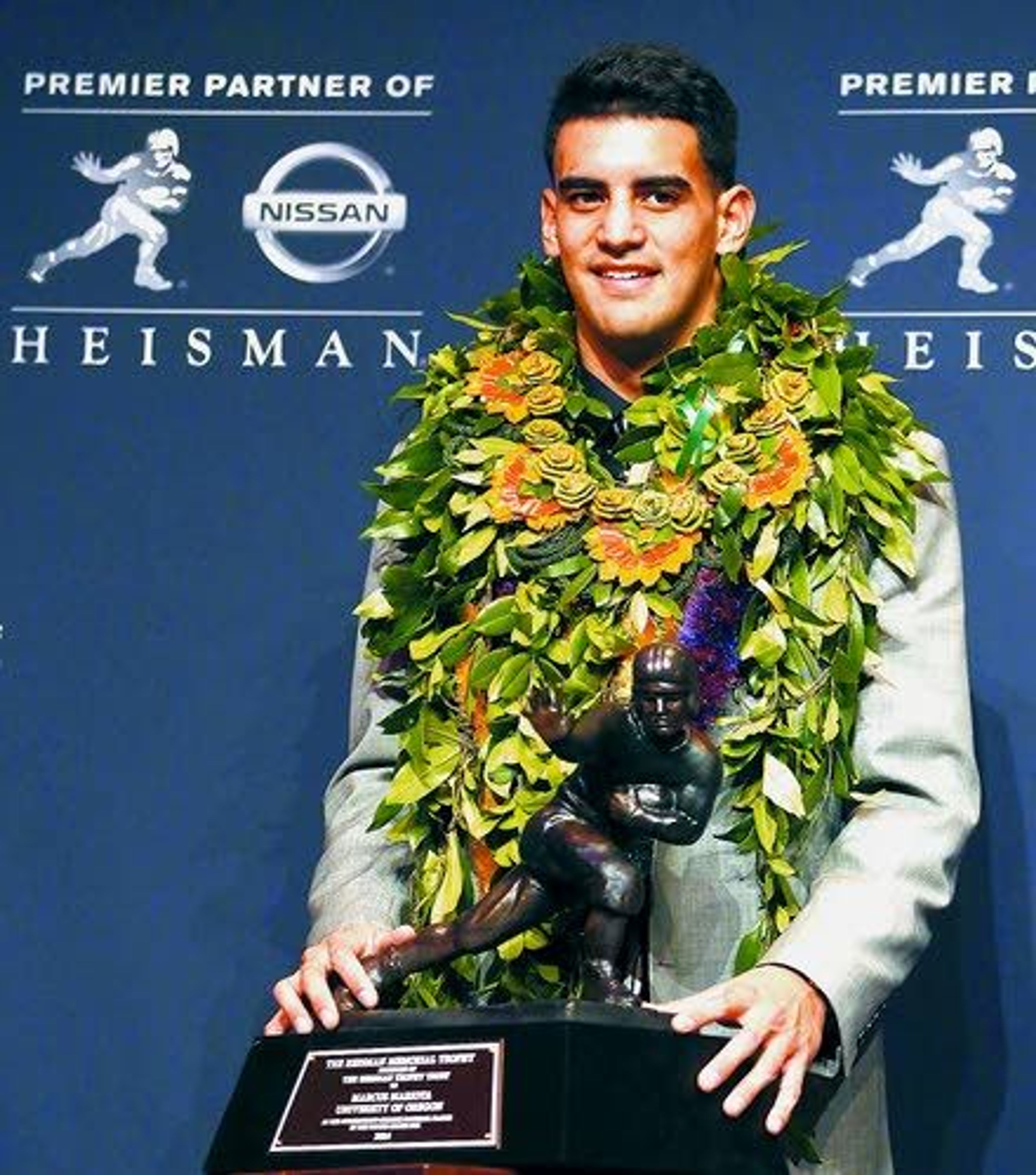 Oregon quarterback Marcus Mariota, wearing a lei from his native Hawaii, poses for photographers after being awarded the Heisman Trophy. The junior became the first Oregon player to win the Heisman on Saturday.