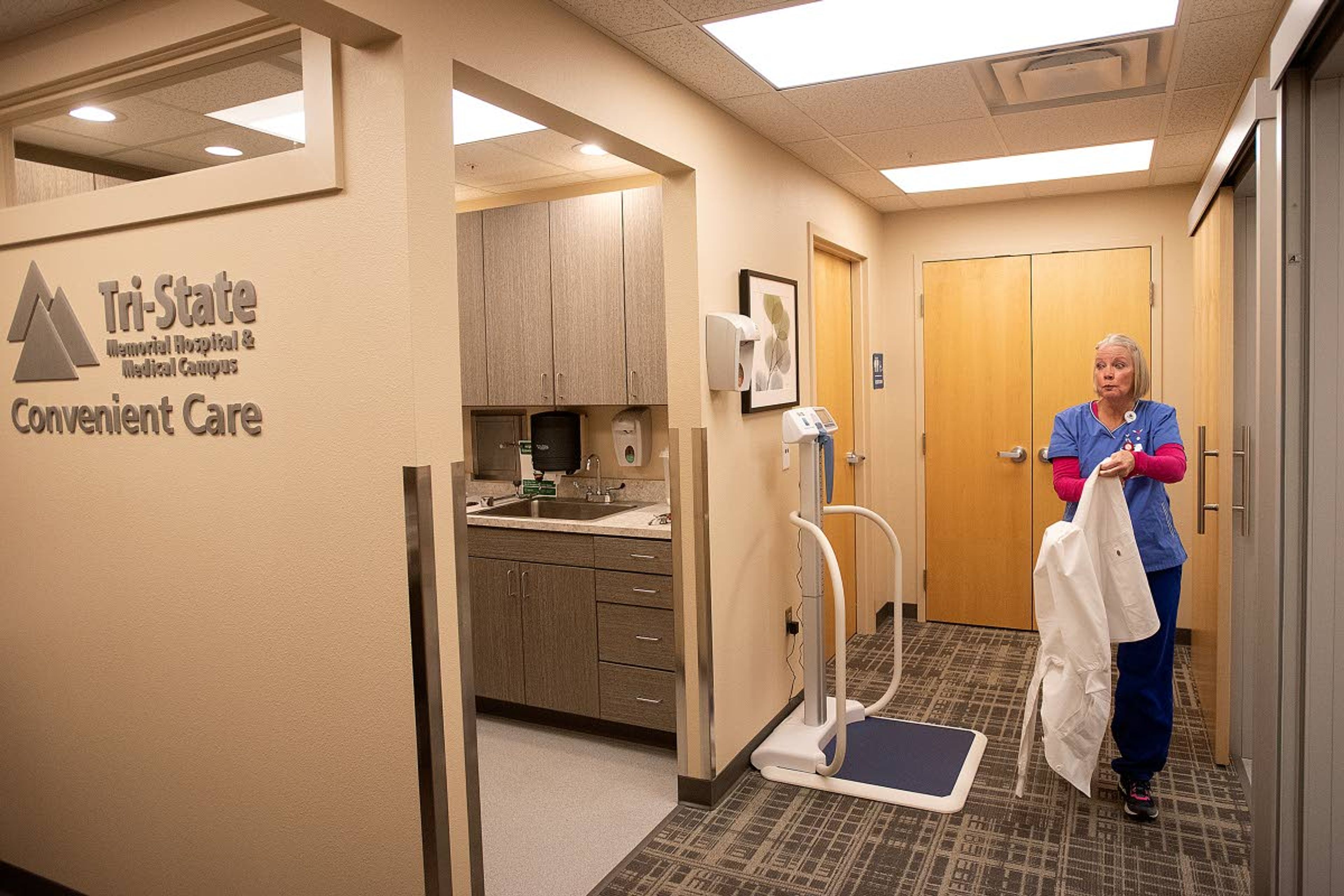 Nurse practitioner Terry Buchanan puts on her lab coat at the Tri-State Memorial Hospital convenient care clinic inside Rosauers grocery store in Lewiston. The Lewiston clinic, along with one in Moscow, are closing this week after less than a year of operation.