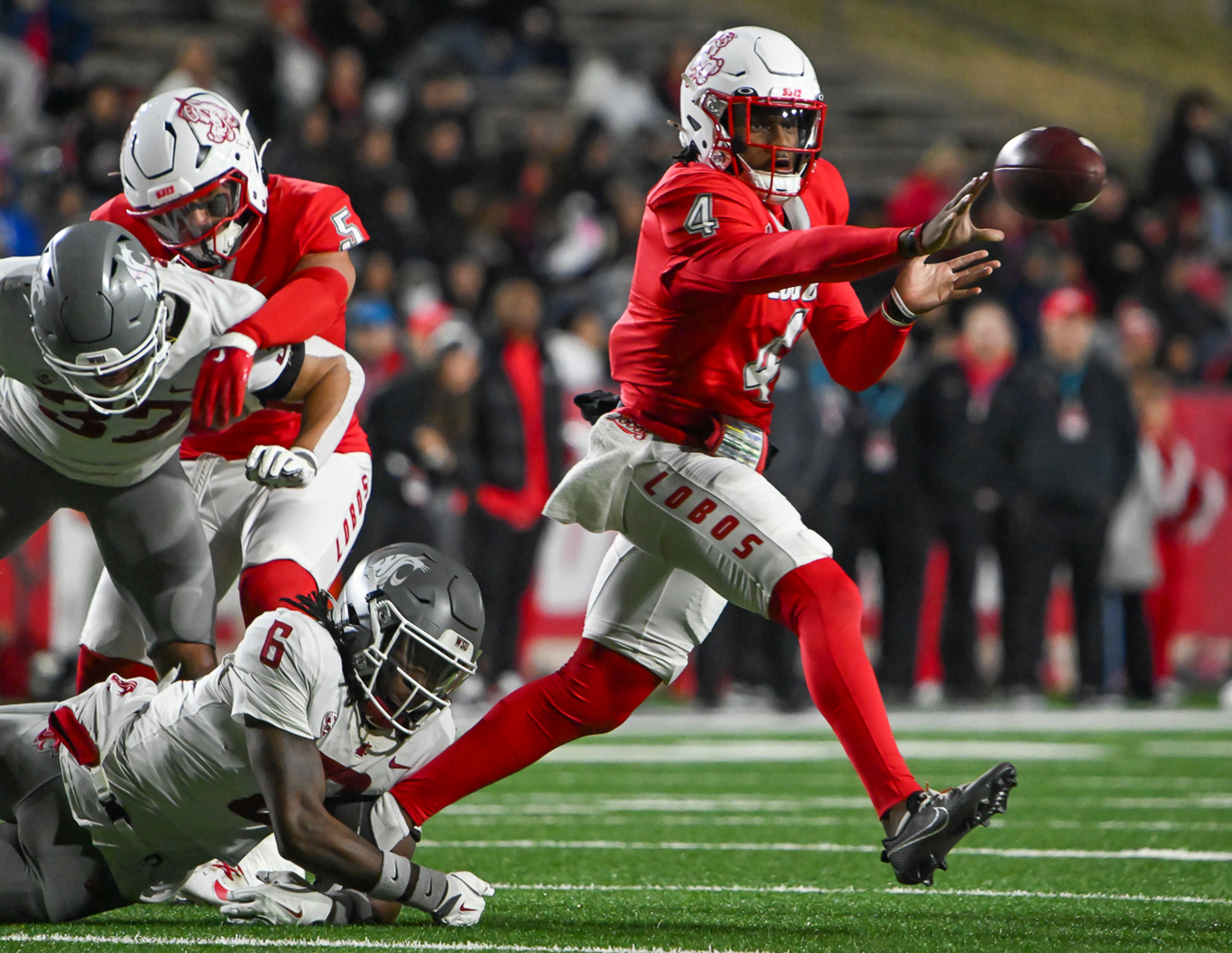 New Mexico quarterback Devon Dampier, right, pitches the ball as Washington State's Adrian Wilson (6) defends during a game on Saturday, Nov. 16, 2024 in Albuquerque, N.M.