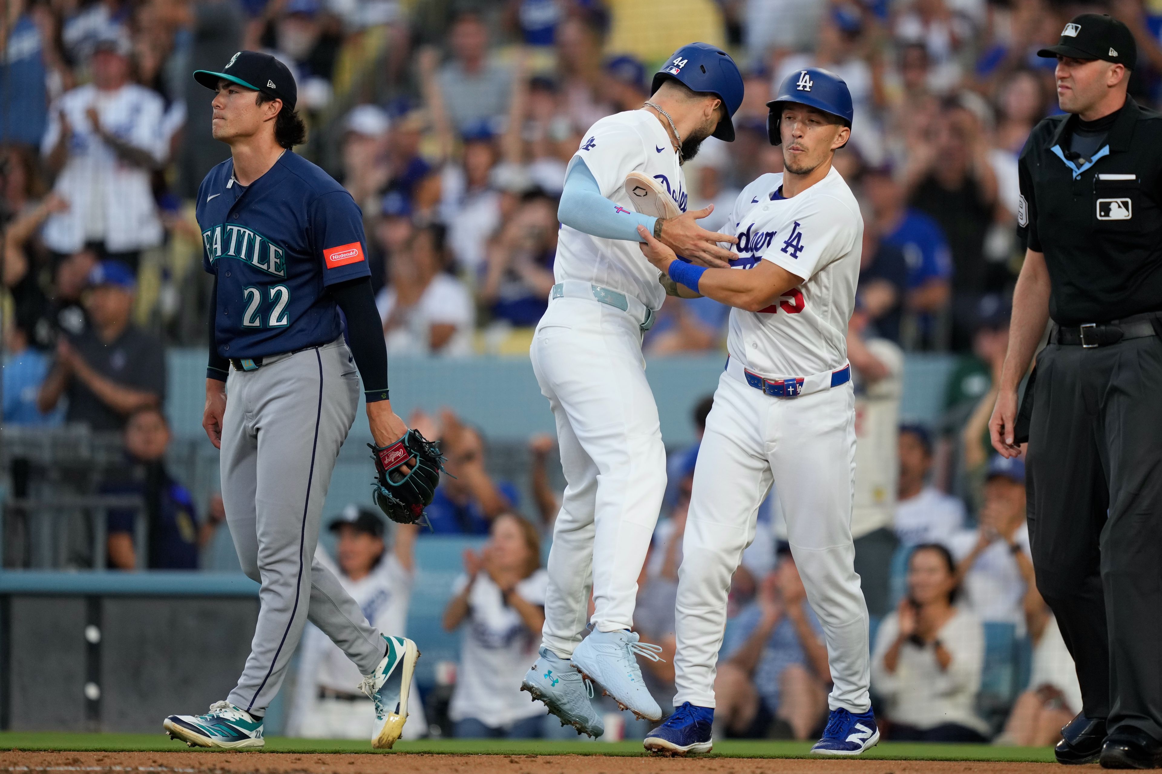 The Dodgers’ Andy Pages, second from left, collides with Tommy Edman, second from right, as he scores on a double by Mookie Betts as the Mariners’ starting pitcher Bryan Woo walks away during the first inning of a baseball game Thursday, in Los Angeles.