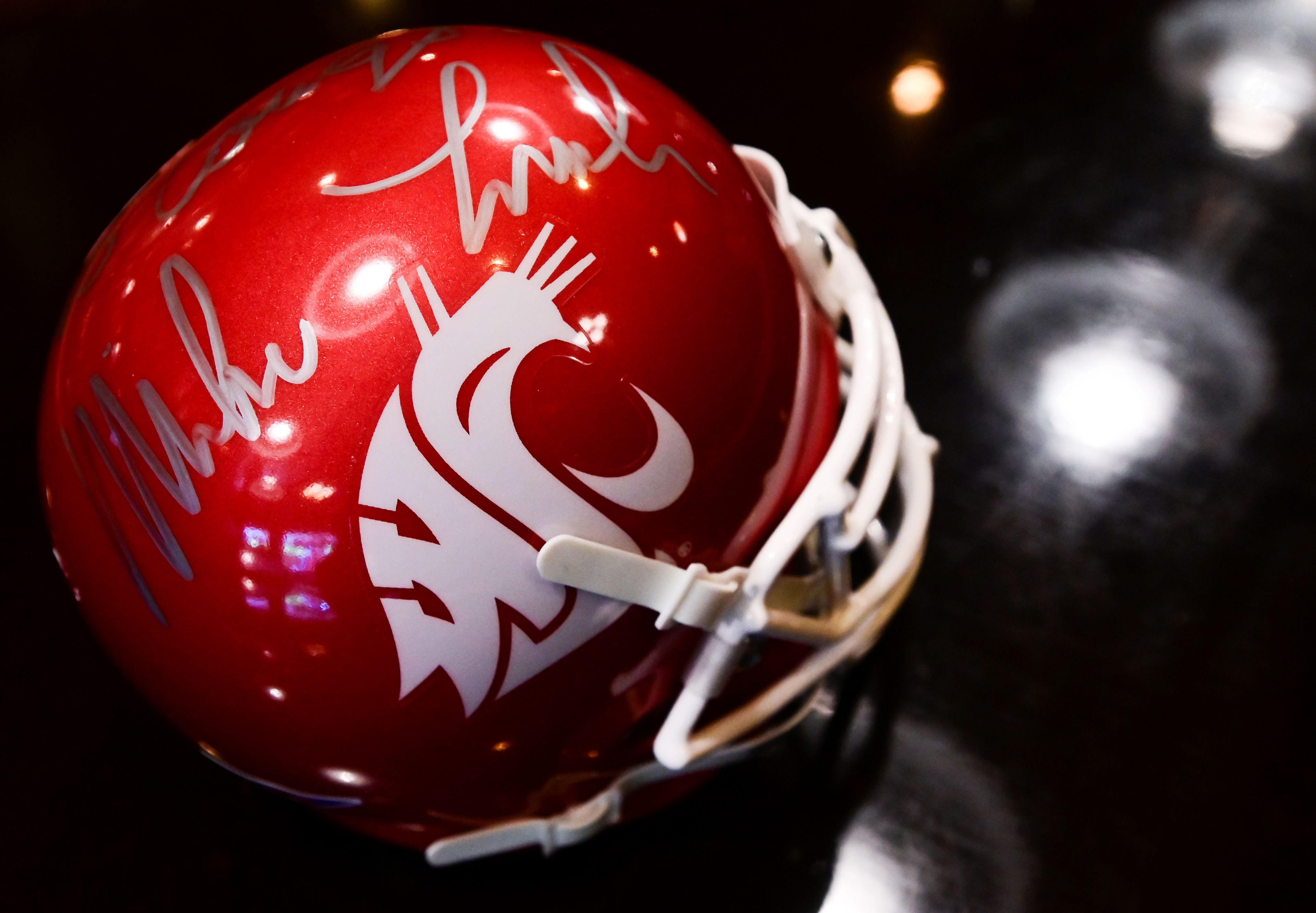 A collector's Washington State Cougars football helmet, signed by former coach Mike Leach, sits on the bartop at Rico's Public House in downtown Pullman on Thursday. Businesses are anticipating a loss of business as the Cougars face realignment.