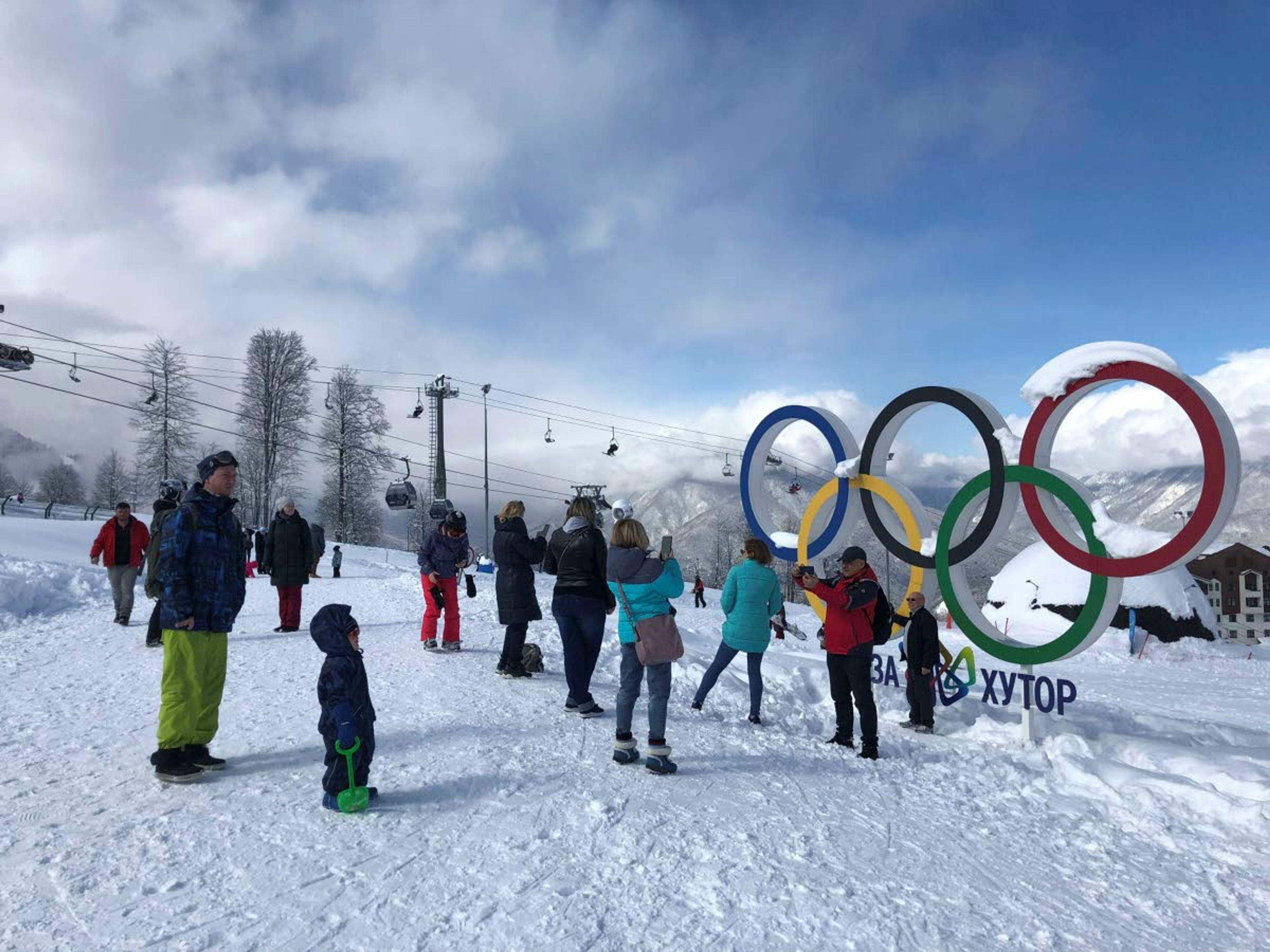 In this photo taken on Sunday, March 3, 2019, tourists walk next to the Olympic rings at the mountain resort of Krasnaya Polyana near the Black Sea resort of Sochi, southern Russia. In the five years since the Sochi Olympics, Russians have been flocking south to enjoy their subtropical ski slopes. (AP Photo/James Ellingworth)