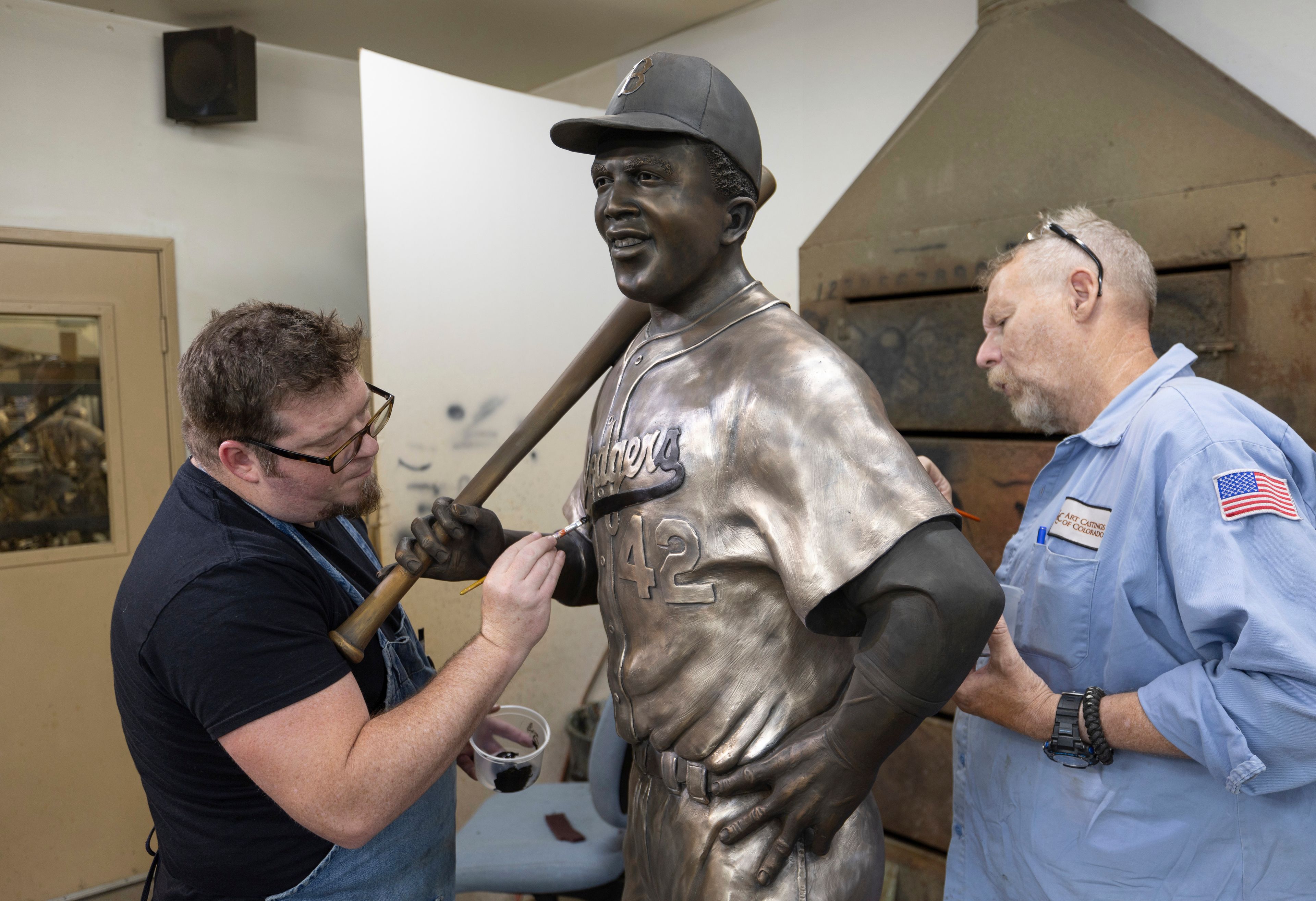 Nate Ford, left, and Jeff Herndon apply finishing touches to a statue of baseball hall-of-famer and civil rights pioneer Jackie Robinson in Loveland, Colo., on Wednesday, July 24, 2024. (Travis Heying/The Wichita Eagle via AP)