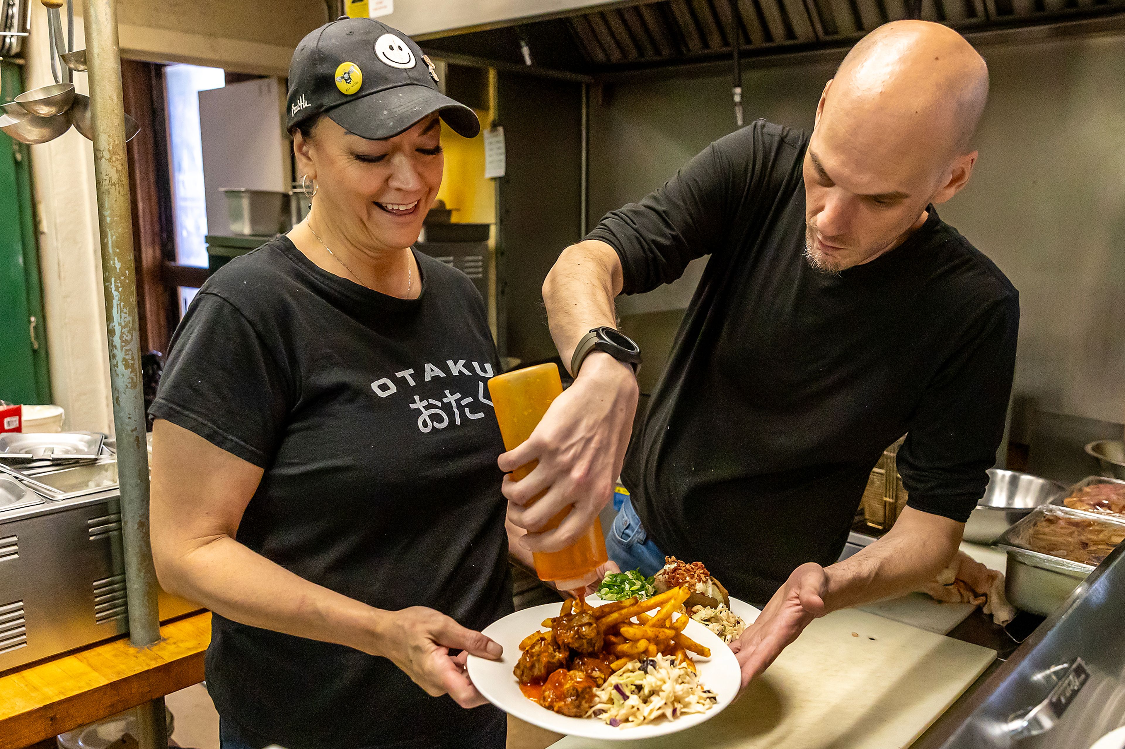 Ryan M Williams adds some sauce to a plate of sweet chili bites held by Tina Poe at Seasons Bites and Burgers Wednesday in Lewiston.