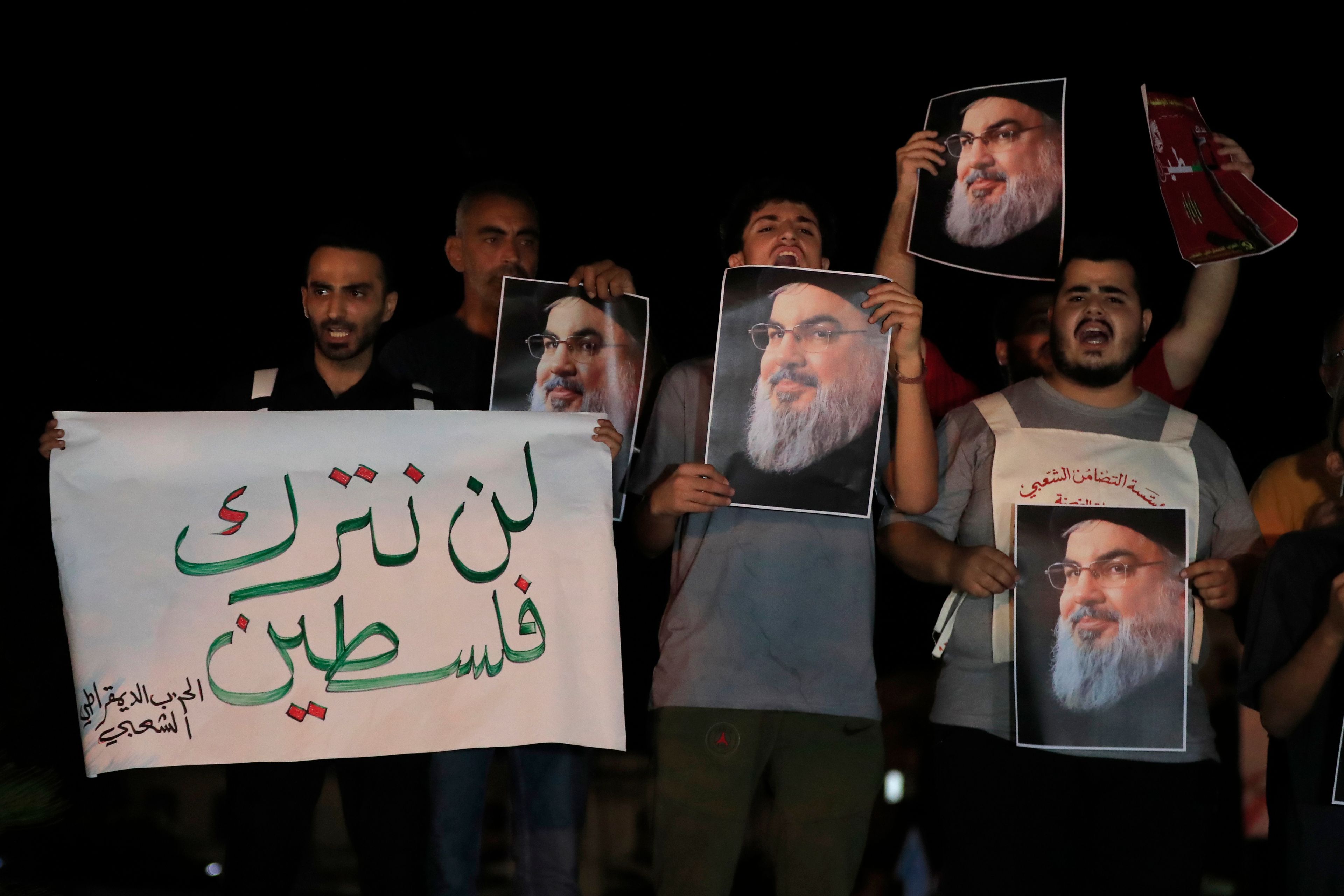 Lebanese and Palestinian men hold portraits of Hezbollah leader Sayyed Hassan Nasrallah and an Arabic placard that reads:"Will not keep Palestine," as they shout slogans during a protest in the southern port city of Sidon, Lebanon, Saturday, Sept. 28, 2024. (AP Photo/Mohammed Zaatari)