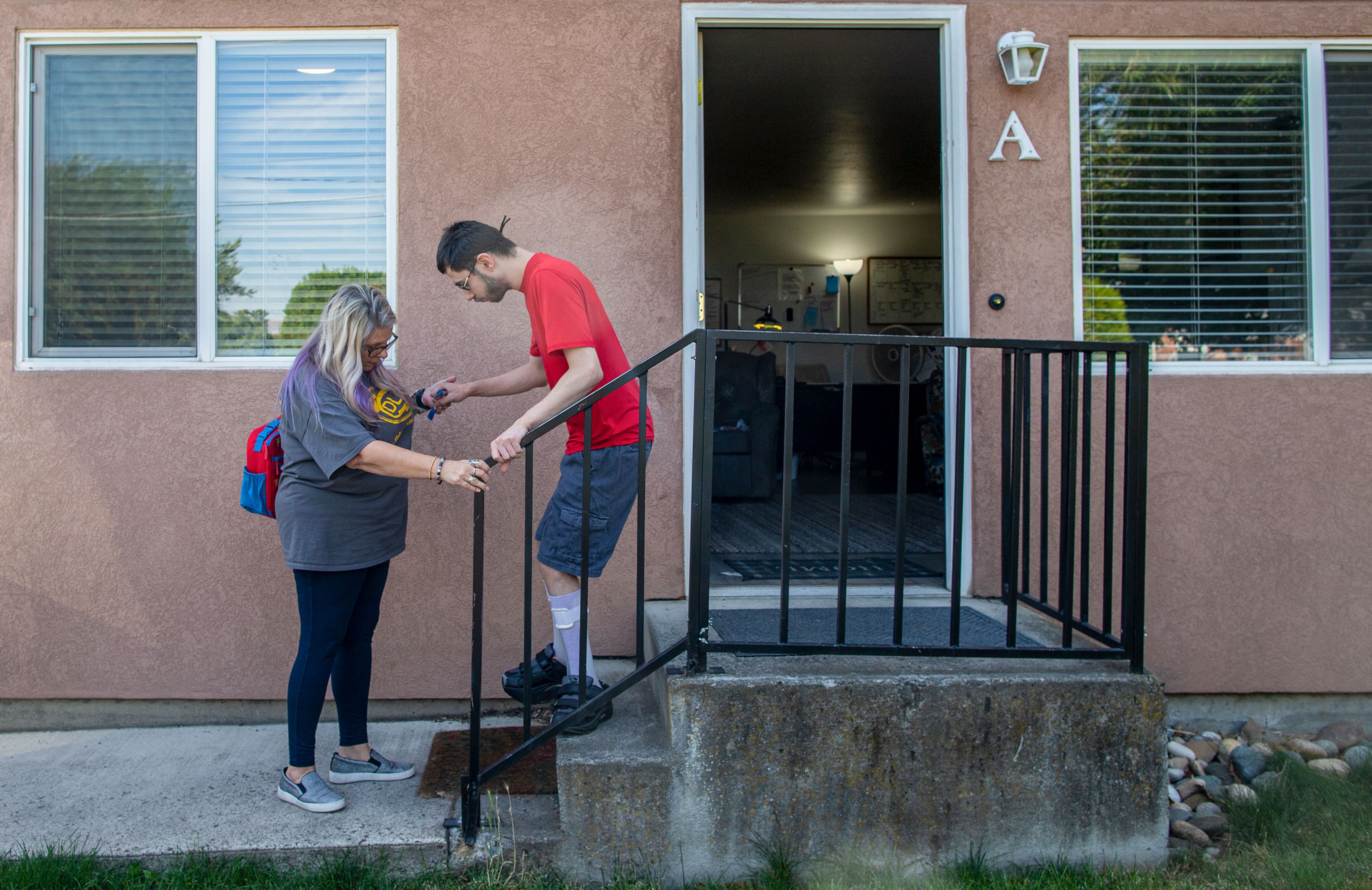 24-Hour House Lead Jill Grant helps Opportunities Unlimited Inc. client Kees Beehner down the steps of his supported living apartment in Lewiston on Sept. 21.