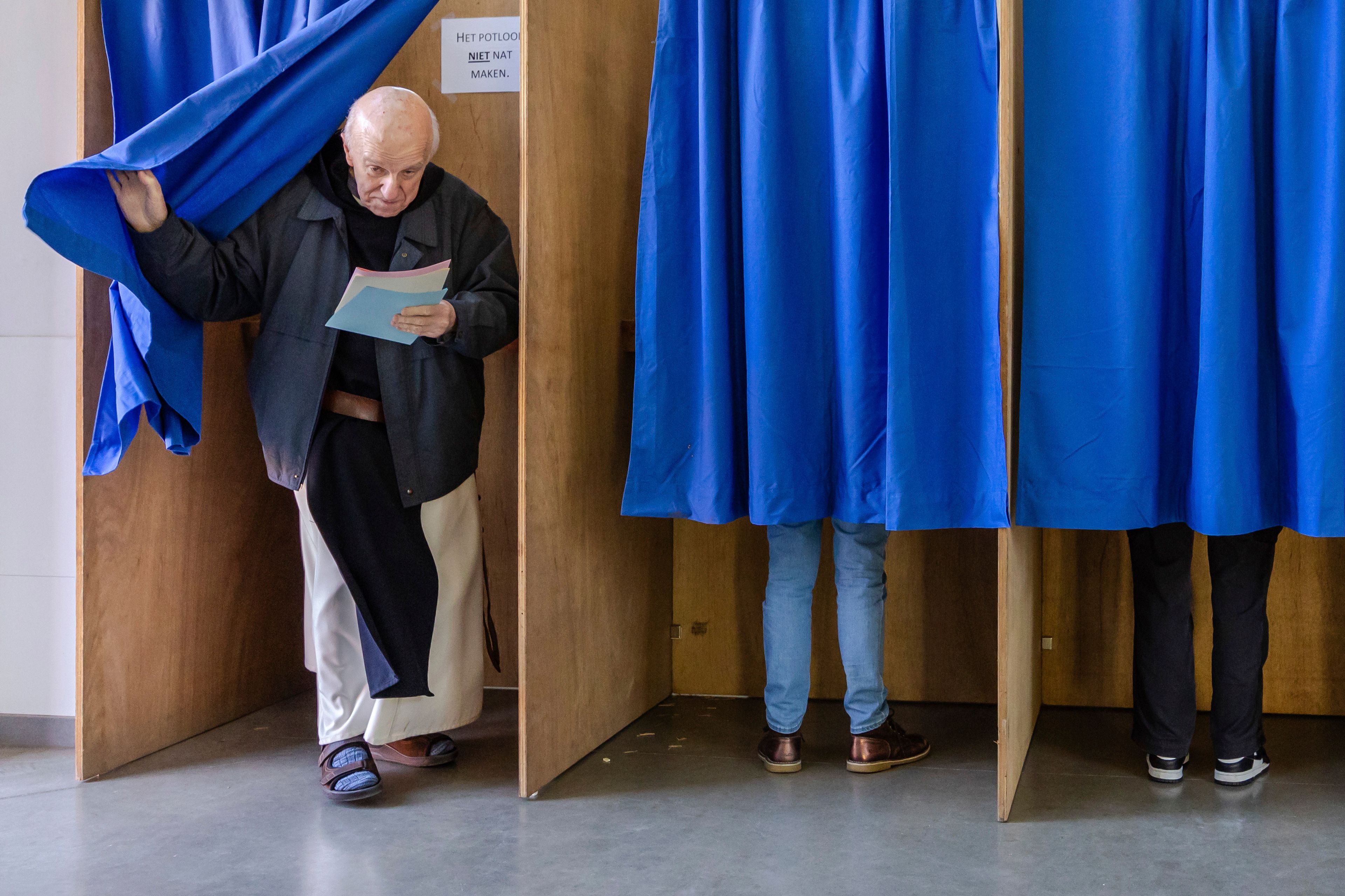 A monk from the Sint-Sixtus Abbey opens the curtain to a voting booth after casting his vote in Vleteren, Belgium, Sunday, June 9, 2024. Polling stations opened across Europe on Sunday as voters from 20 countries cast ballots in elections that are expected to shift the European Union's parliament to the right and could reshape the future direction of the world's biggest trading bloc.