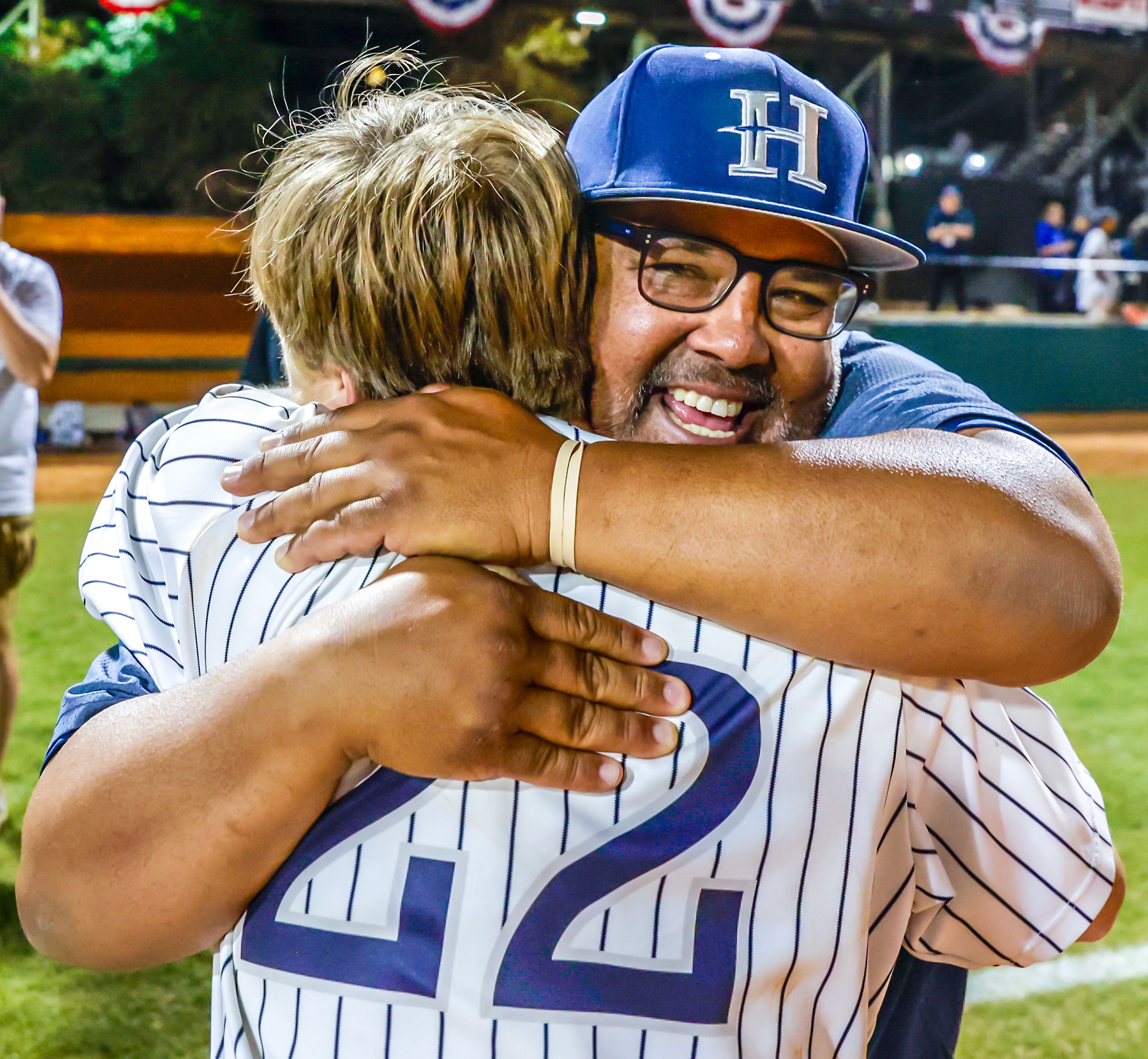 Hope International Head Coach Larry Mahoney hugs Ryan Lamastra after defeating Tennessee Wesleyan 13-6 in Game 19 of the NAIA World Series at Harris Field Friday in Lewiston.