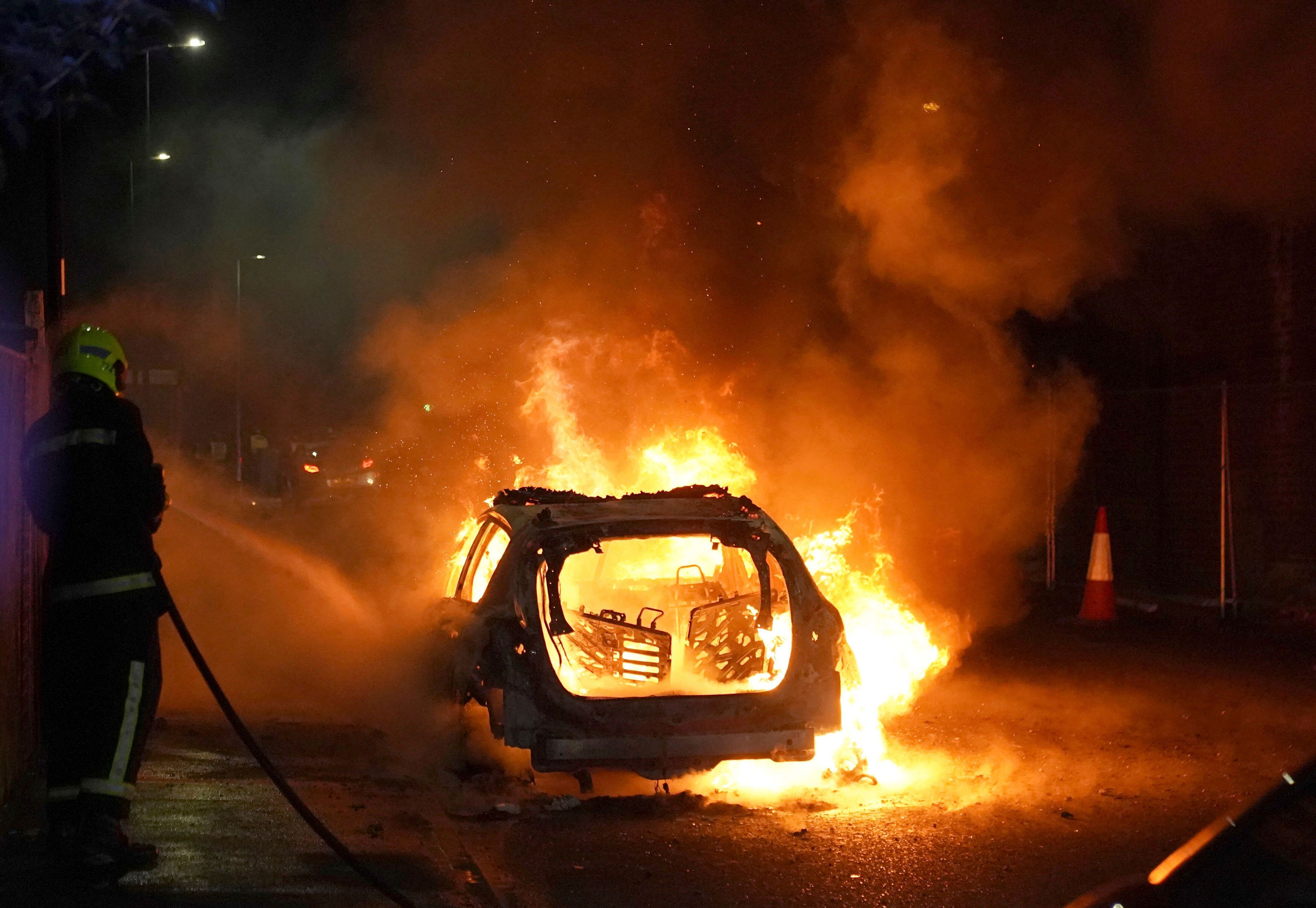 Firefighters tend to a burning police car as police officers are deployed on the streets of Hartlepool, England, following a violent protest in the wake of the killing of three girls who were fatally stabbed in northwest England, Wednesday, July 31, 2024. (Owen Humphreys/PA via AP)