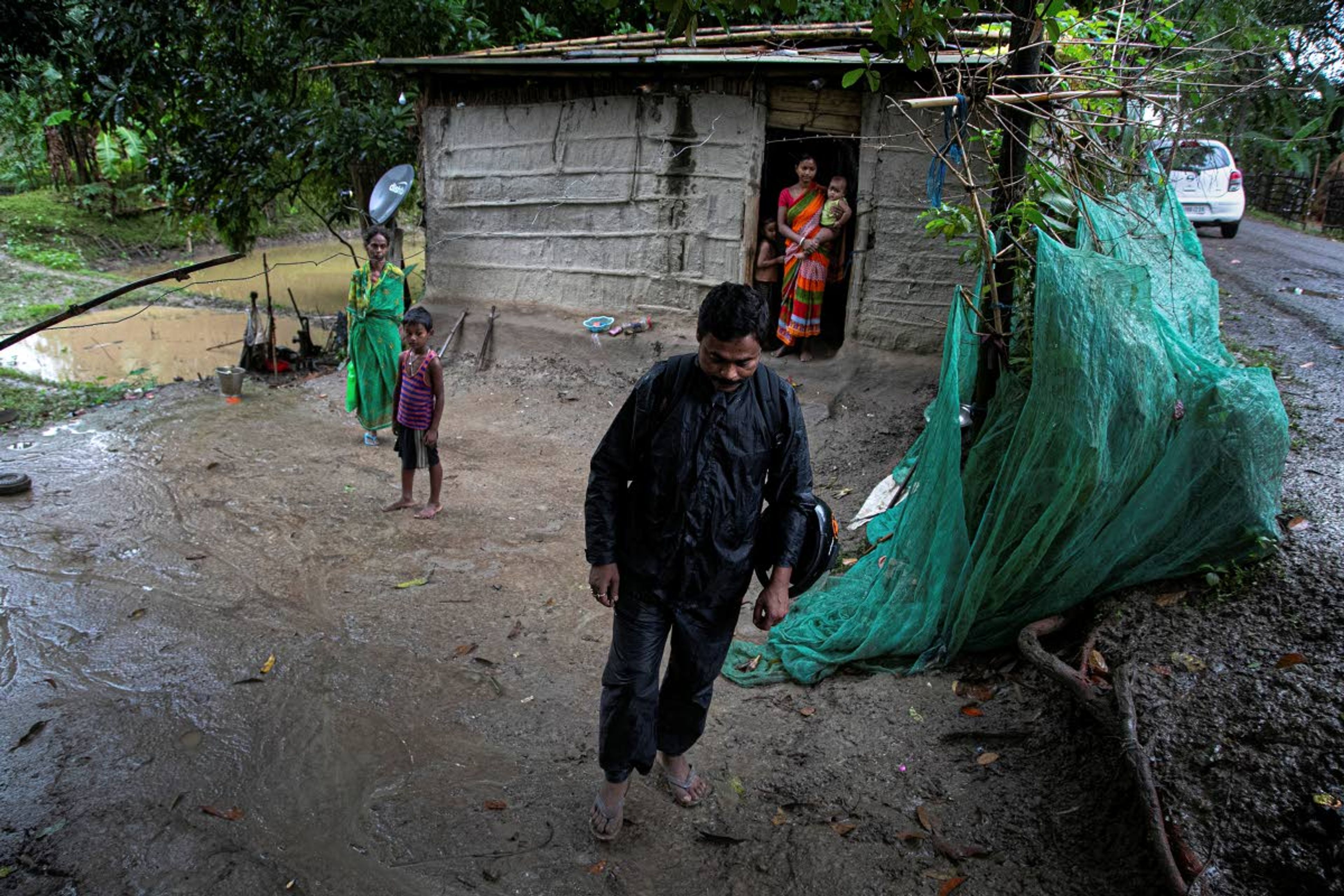 Ramananda Sarkar, 43, leaves home after visiting his family and talking to them from a distance in Theng Bhanga village, in Morigaon district, India, Tuesday, Sept. 22, 2020. Sarkar, who was deep in debt and desperate for money, took the job of lighting funeral pyres after failing to pay back a loan he'd taken to start selling sugarcane juice on a wooden cart. Dealing with corpses is a stigma that's only been made worse by the coronavirus, which has killed more than 100,000 people in India out of 6.4 million reported infections. After a month and a half of not seeing his wife and three sons, Sarkar snuck into his village in the middle of a recent rainy night and was able to spend 15 minutes with them and leave them some money. (AP Photo/Anupam Nath)