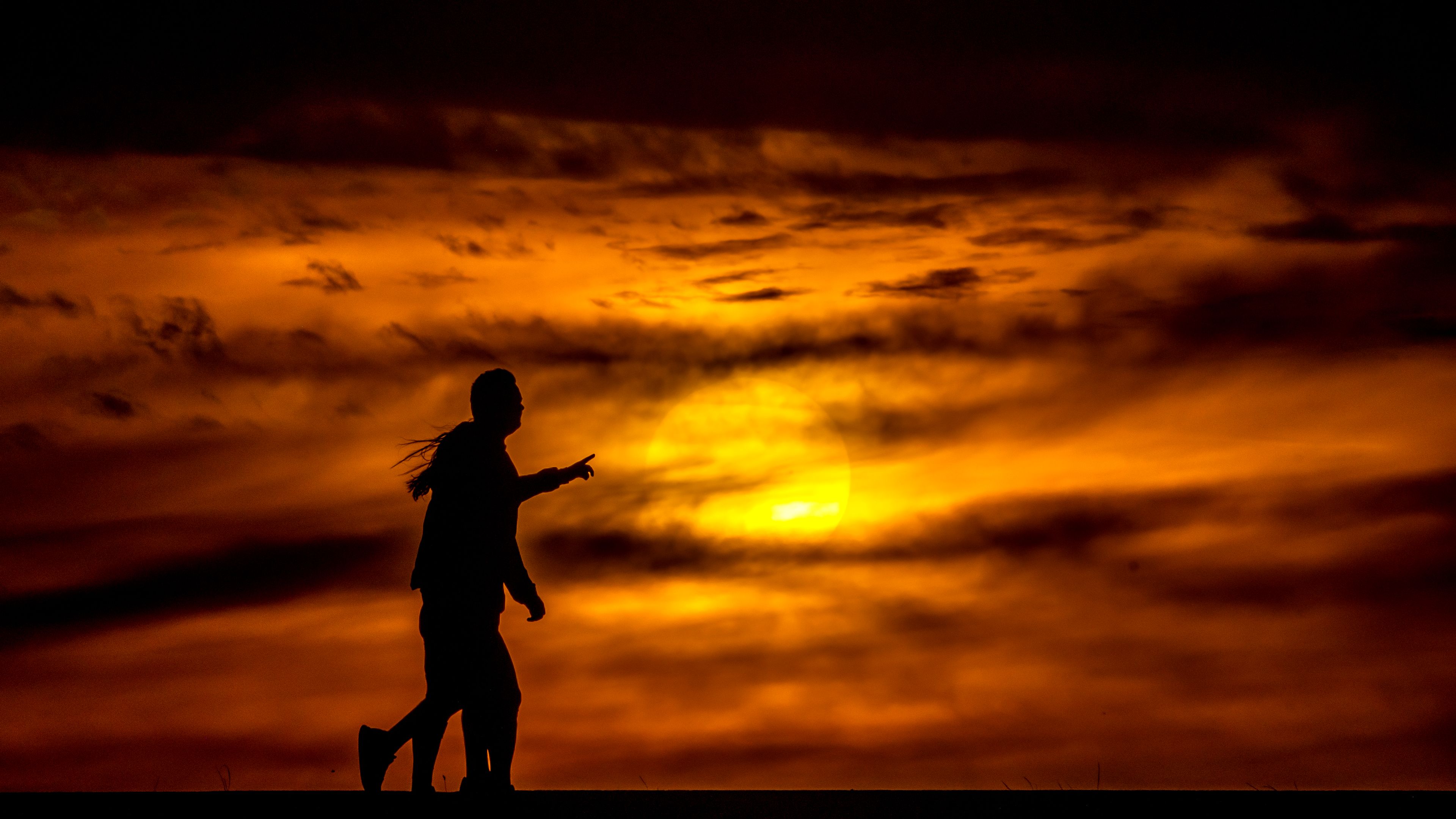 People walk down the Lewiston Levee Parkway Trail as the sun sets Wednesday in Lewiston.,