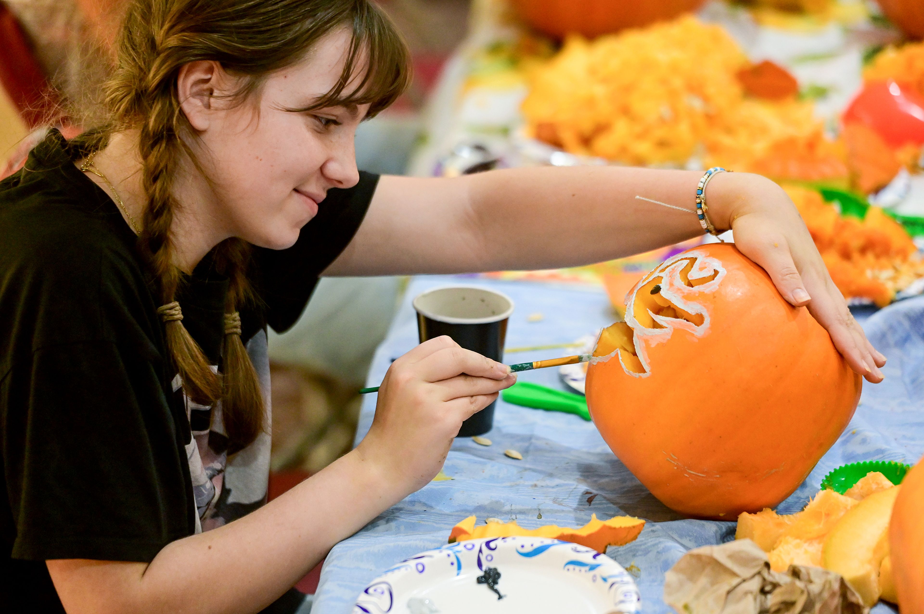 Iris Carpenter, a freshman at Washington State University, paints along the carved edges of a design on a pumpkin Wednesday in the lounge of the WSU Student Recreation Center in Pullman. Students were welcome to carve and decorate their pumpkins after picking from the AquaPatch.,