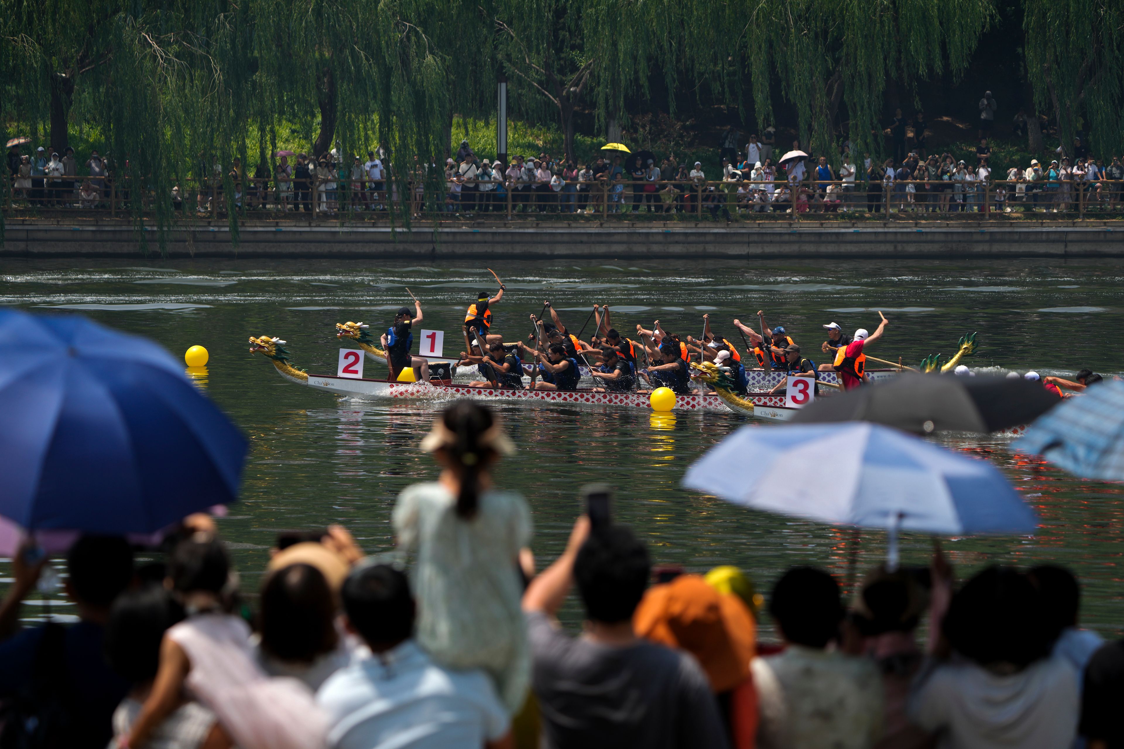 People watch the dragon boat races during the Dragon Boat Festival at a canal in Tongzhou, outskirts of Beijing, Monday, June 10, 2024. The Duanwu Festival, also known as the Dragon Boat Festival, falls on the fifth day of the fifth month of the Chinese lunar calendar and is marked by eating rice dumplings and racing dragon boats.