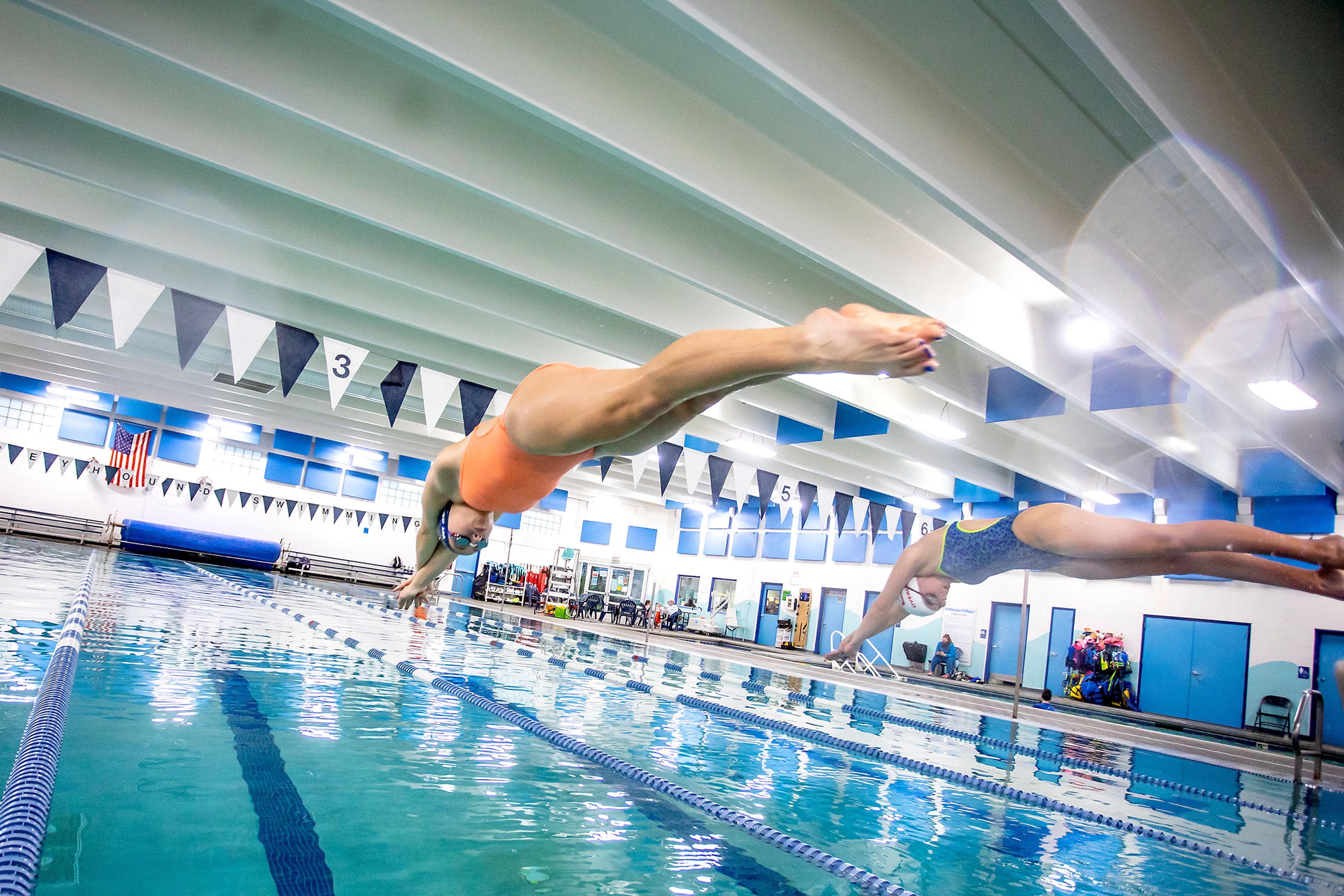 Madi Weber (left) and Estelle Uperuaga leaps into the water during practice at the Pullman Aquatic Center on Wednesday.