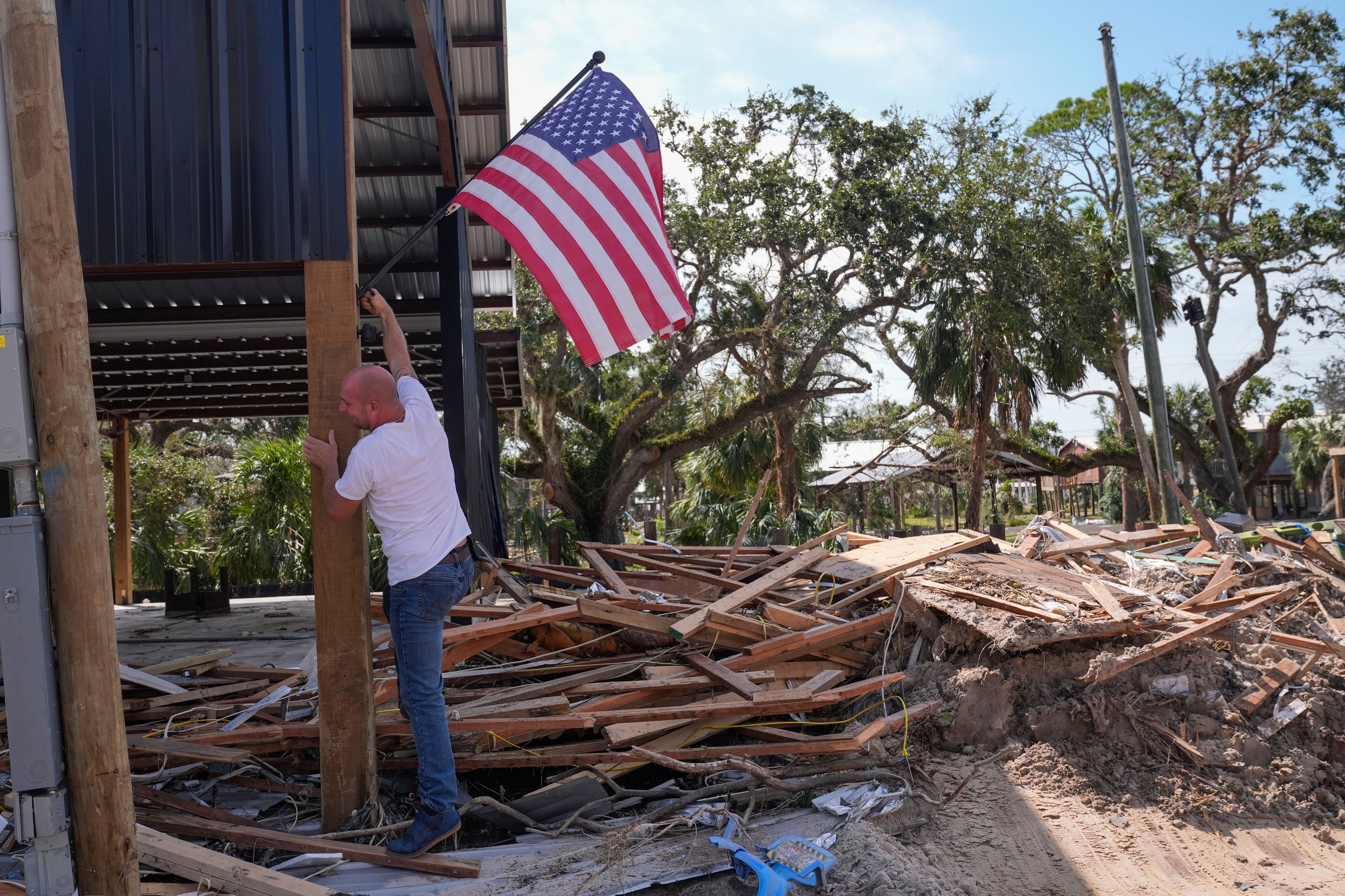 John Taylor puts up an American flag on his destroyed property in the aftermath of Hurricane Helene, in Horseshoe Beach, Fla., Saturday, Sept. 28, 2024. (AP Photo/Gerald Herbert)