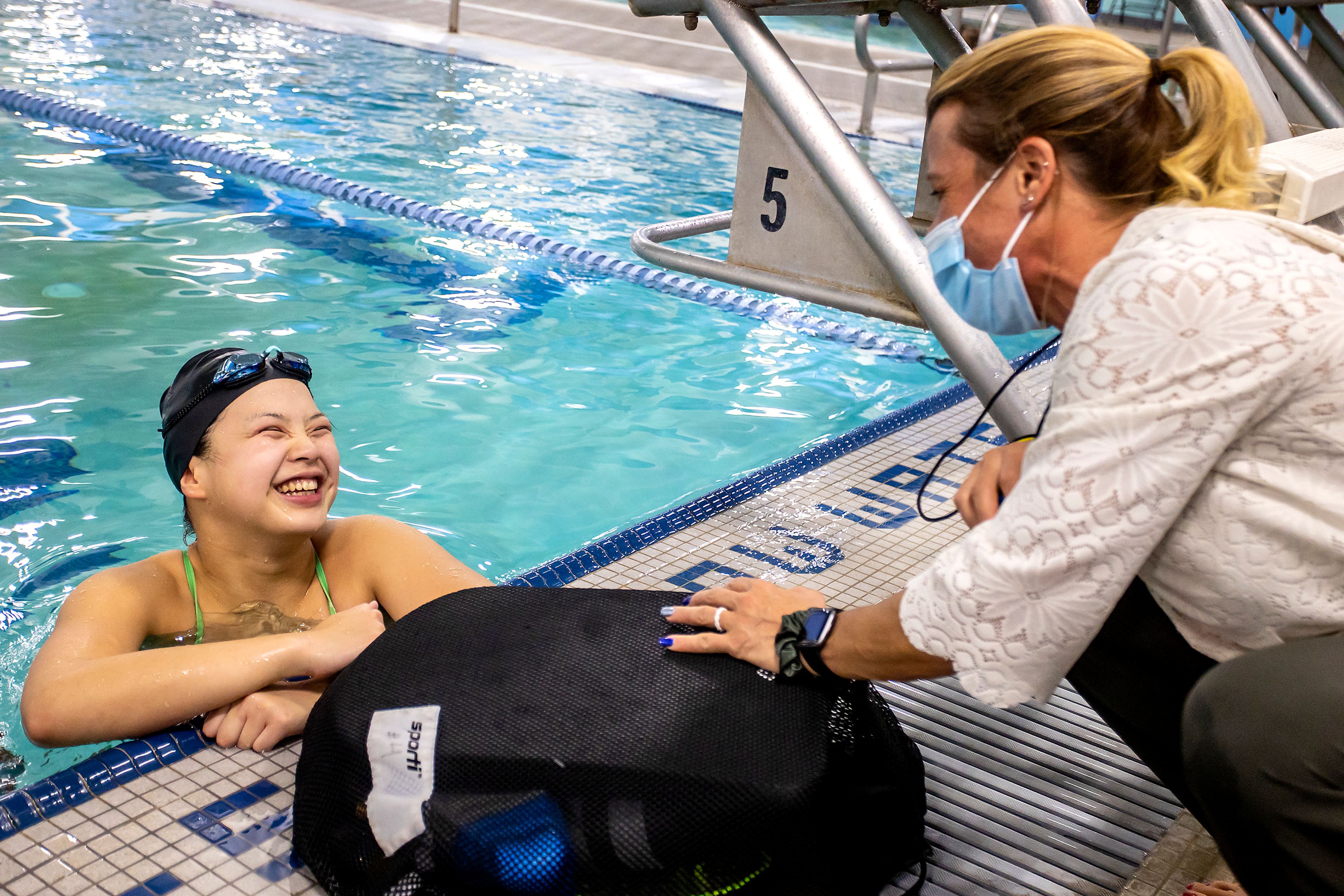 Nelly Peng shares a laugh with her coach Amy Ripley during practice at the Pullman Aquatic Center on Wednesday.