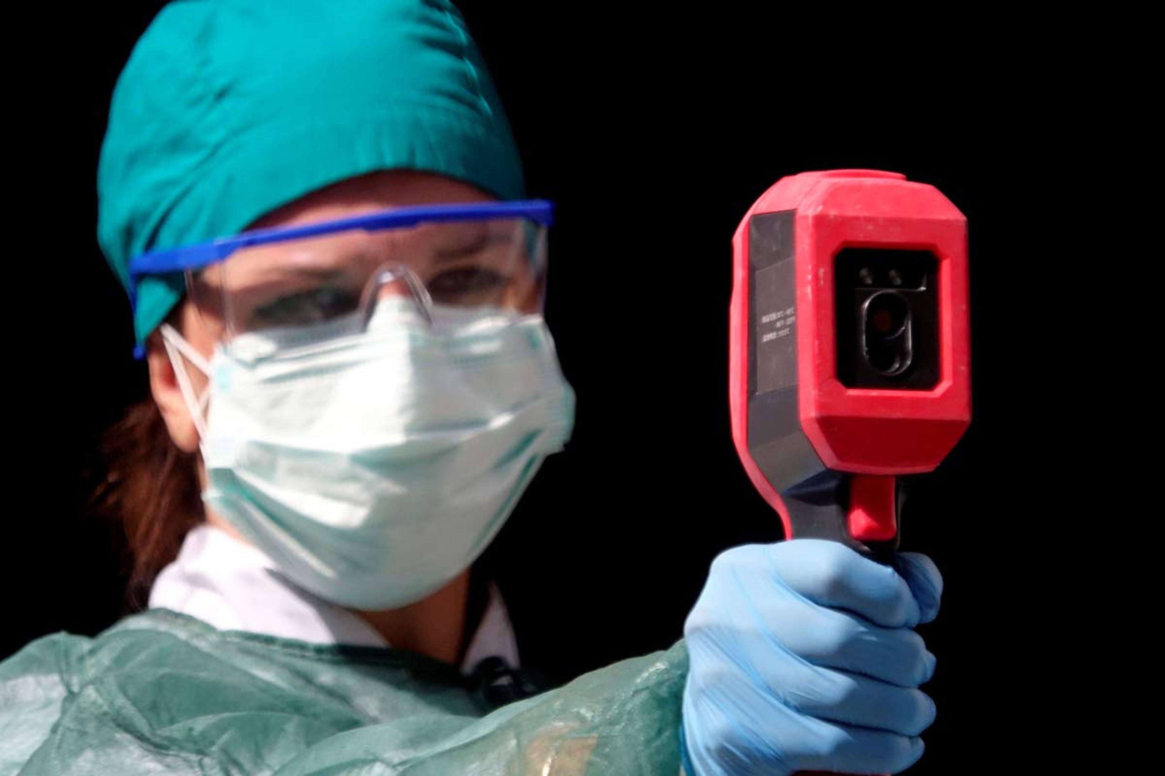 A healthcare worker measures body temperature as a precaution against the spread of the new coronavirus in COVID-19 hospital in Sarajevo, Bosnia, Monday, July 27, 2020. Regional WHO office in Bosnia expressed its concern with recent reports that medical institutions around the country are closing to maximum capacity as recent spike in COVID-19 infections are reaching record levels. (AP Photo/Eldar Emric)