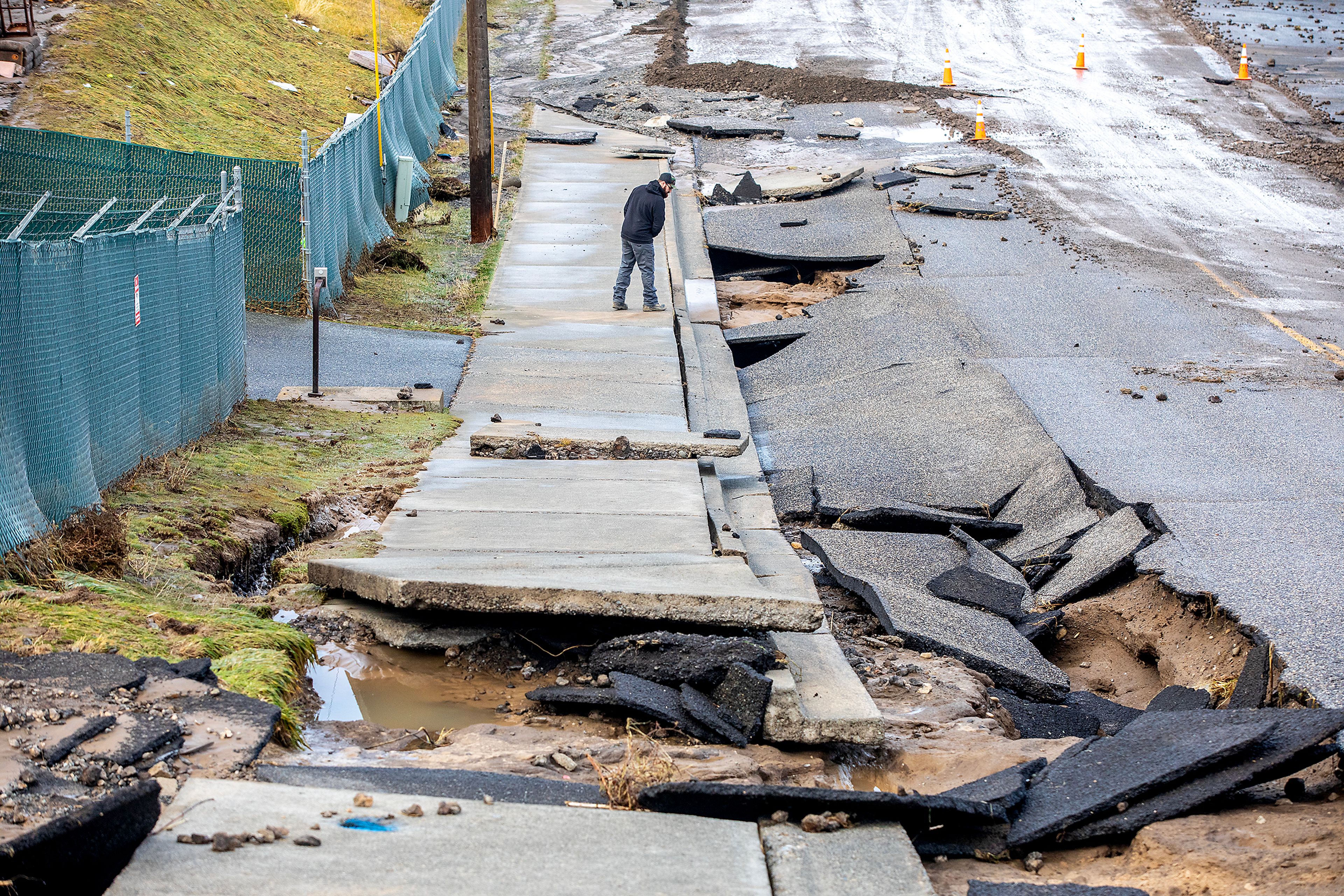 A man working at the scene looks over the cracked pavement along 16th Avenue where a water reservoir burst in the early hours of Wednesday in Lewiston.