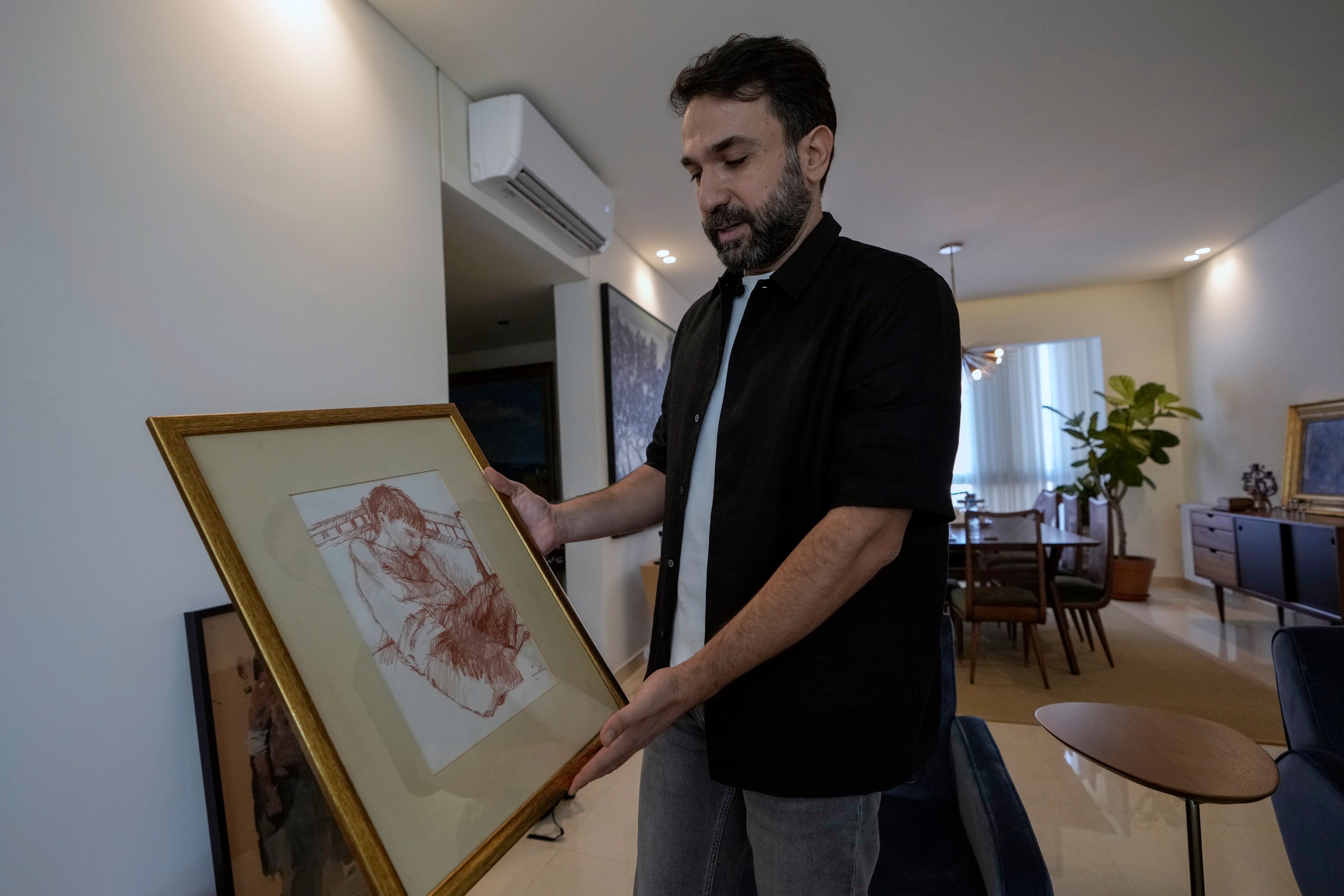 Lubnan Baalbaki shows a sketch depicting him while he was asleep drawn by his late father, during an interview with The Associated Press at his house in Geitawi, Beirut, Lebanon, Thursday, Oct. 31, 2024. (AP Photo/Bilal Hussein)