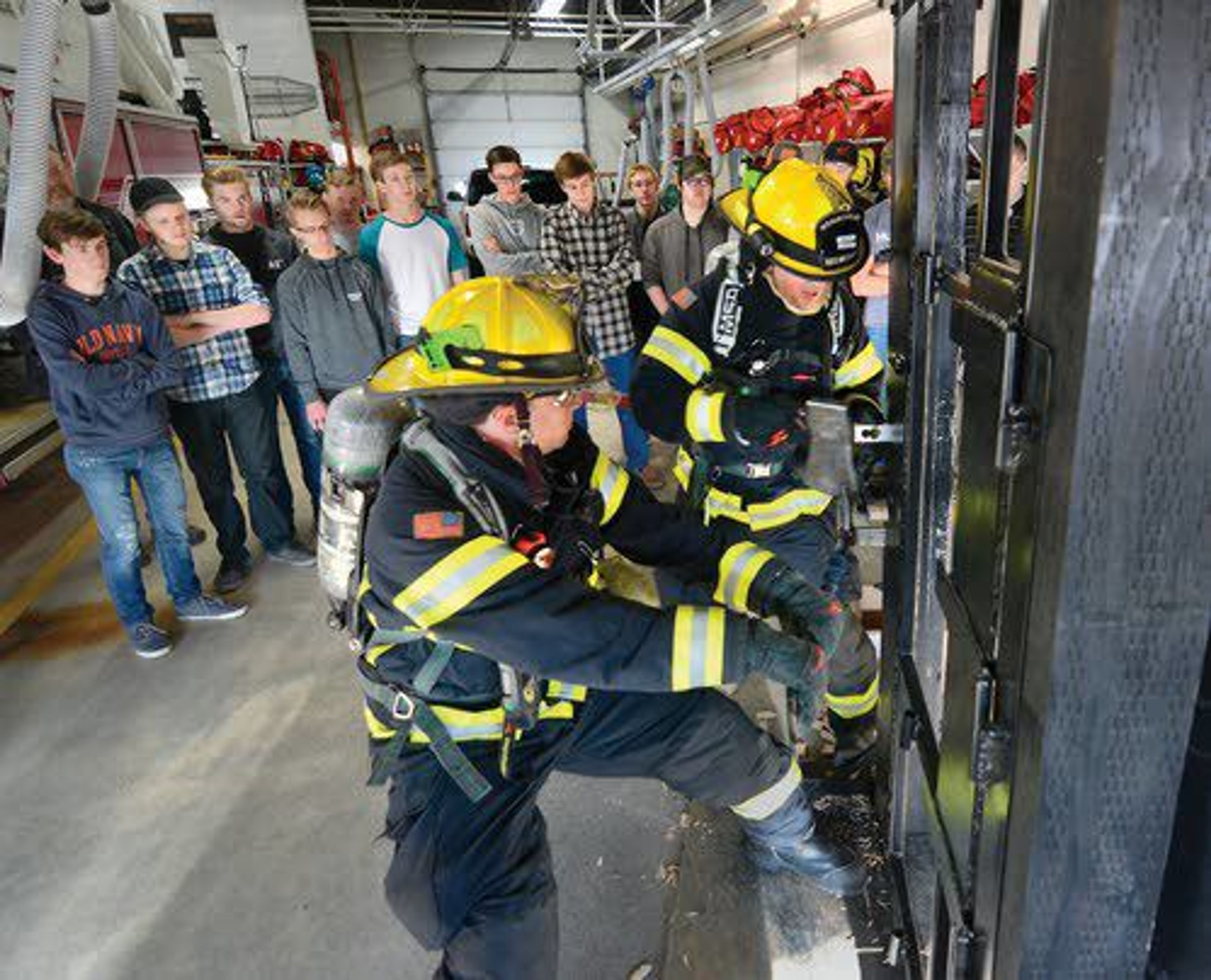 Lewiston reserve firefighters Chris Currie and Chris Jones work an aluminum wedge, milled by Lewiston High School students, into a door-entry trainer.