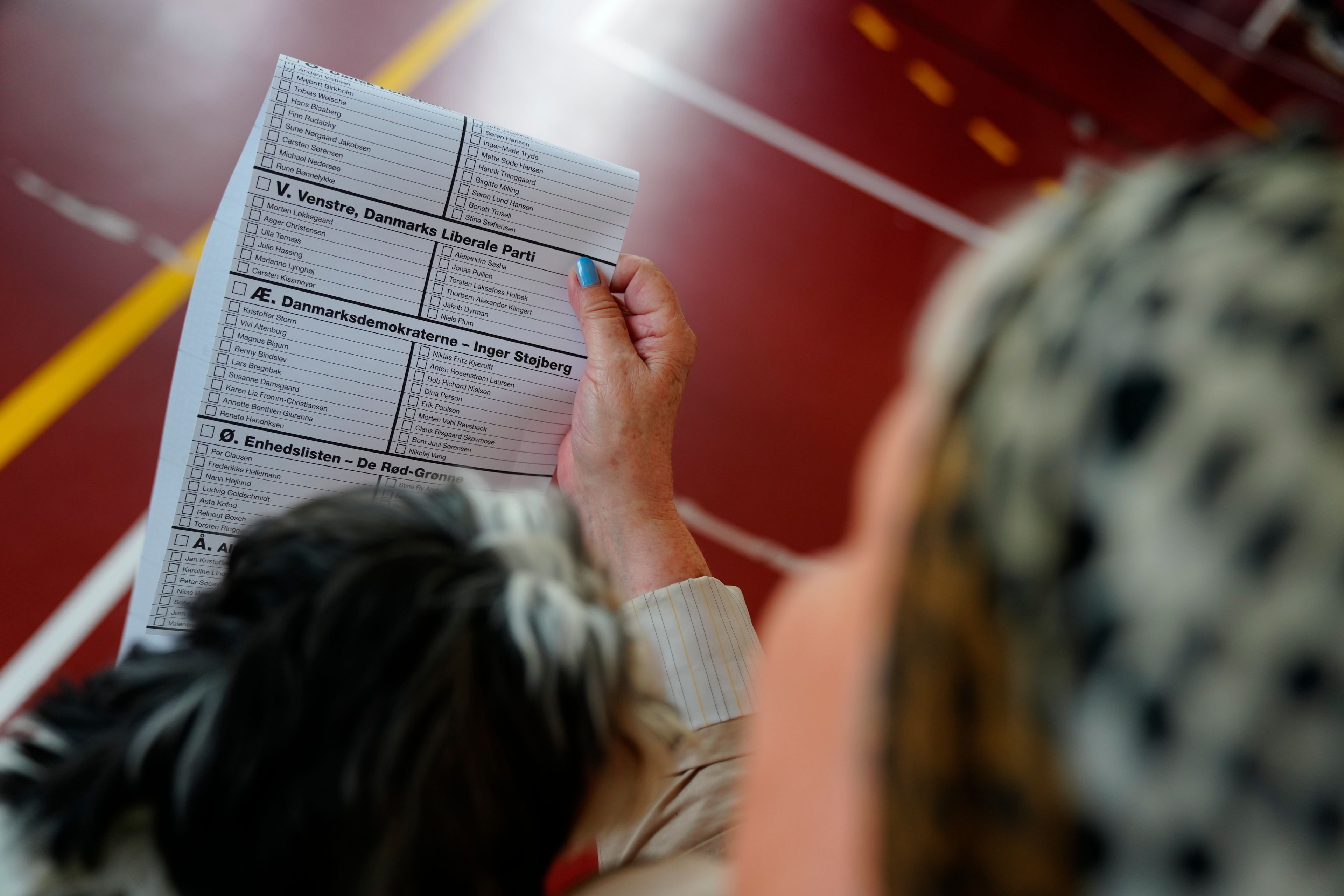 A woman reads the ballot with the names of the candidate before voting, during the European Parliament Election, at Nyboder School, in Copenhagen, Denmark, Sunday, June 9, 2024. Polling stations have opened across Europe as voters from 20 countries cast ballots in elections that are expected to shift the European Union’s parliament to the right and could reshape the future direction of the world’s biggest trading bloc.