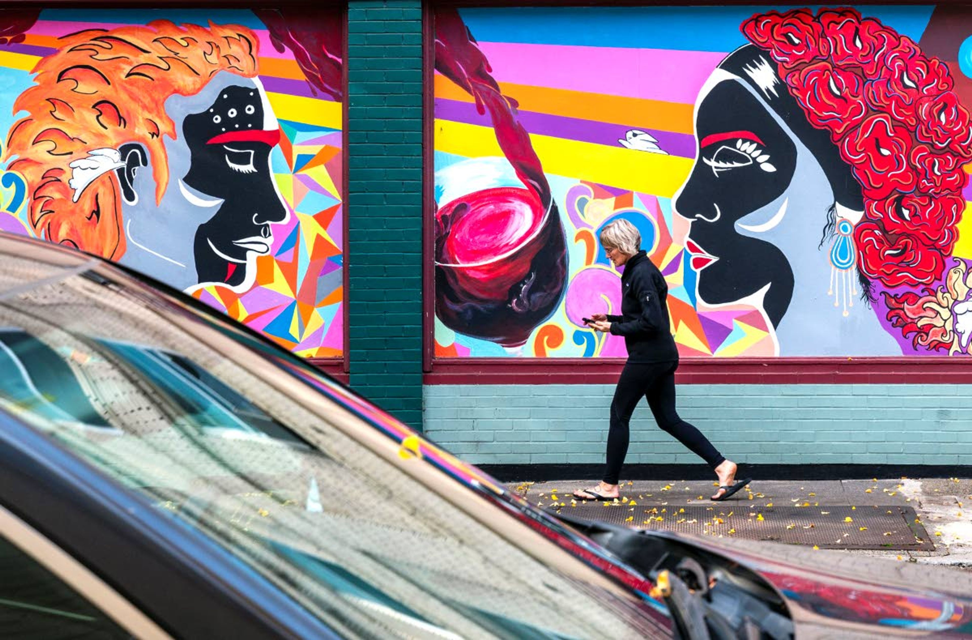 A woman walks past a wine-inspired mural on a building in downtown McMinnville. The town of about 30,000 people has capitalized off its location amidst the wine-crazed Willamette Valley. Wine bars, tasting rooms and wineries are scattered all along the main downtown drag.