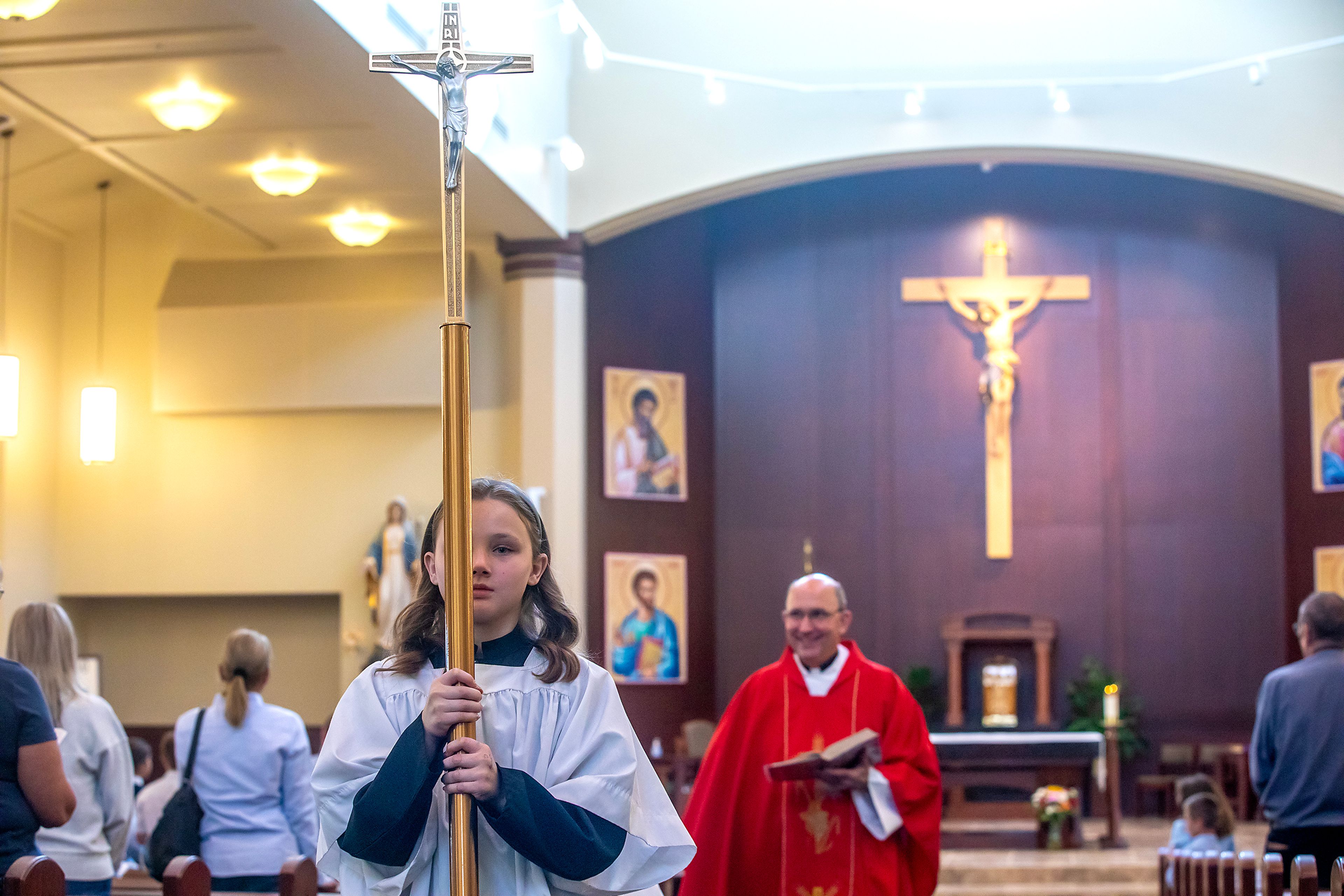 Altar server Claire McCann exits carrying the cross Wednesday at All Saints Catholic Church in the Lewiston Orchards, followed by the Rev. Mike St. Marie.