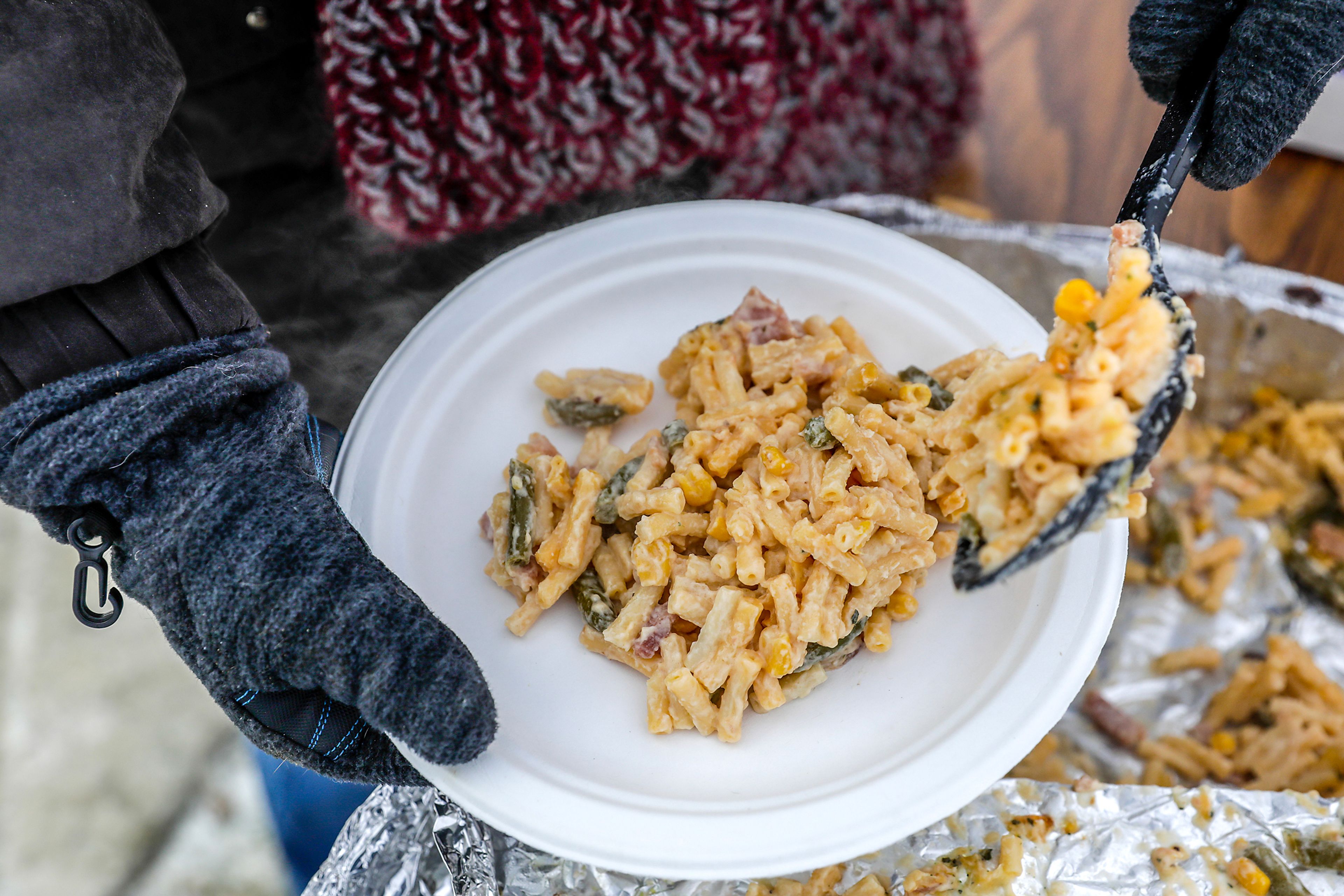 Amanda Cox spoons some food onto a plate for a resident at the homeless camp behind Walmart at a warming tent outside the Chef Store Sunday in Clarkston.