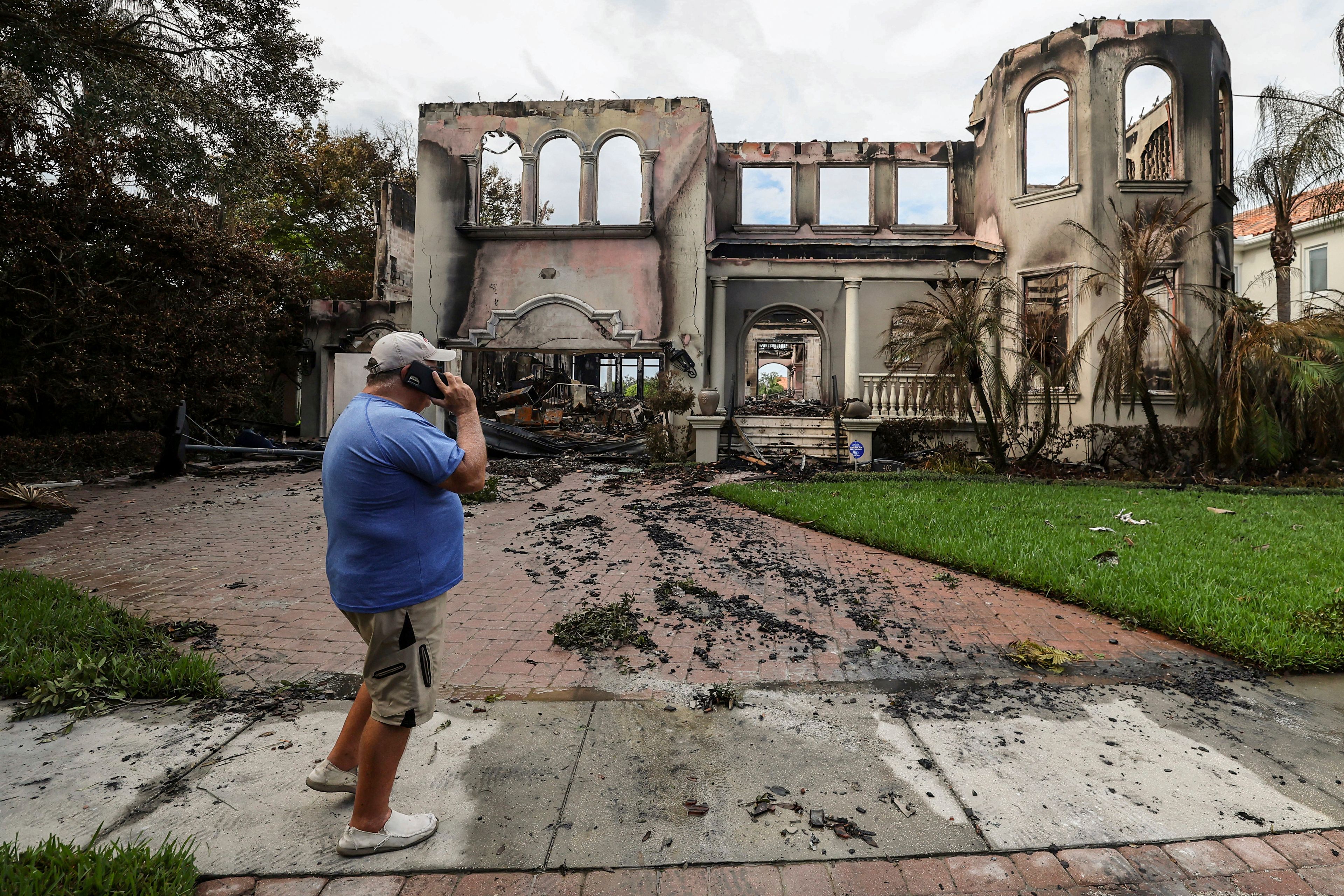 Joe Daum looks at the remains of a friend's home that burned during Hurricane Helene on Davis Island Saturday, Sept. 28, 2024, in Tampa, Fla. (AP Photo/Mike Carlson)