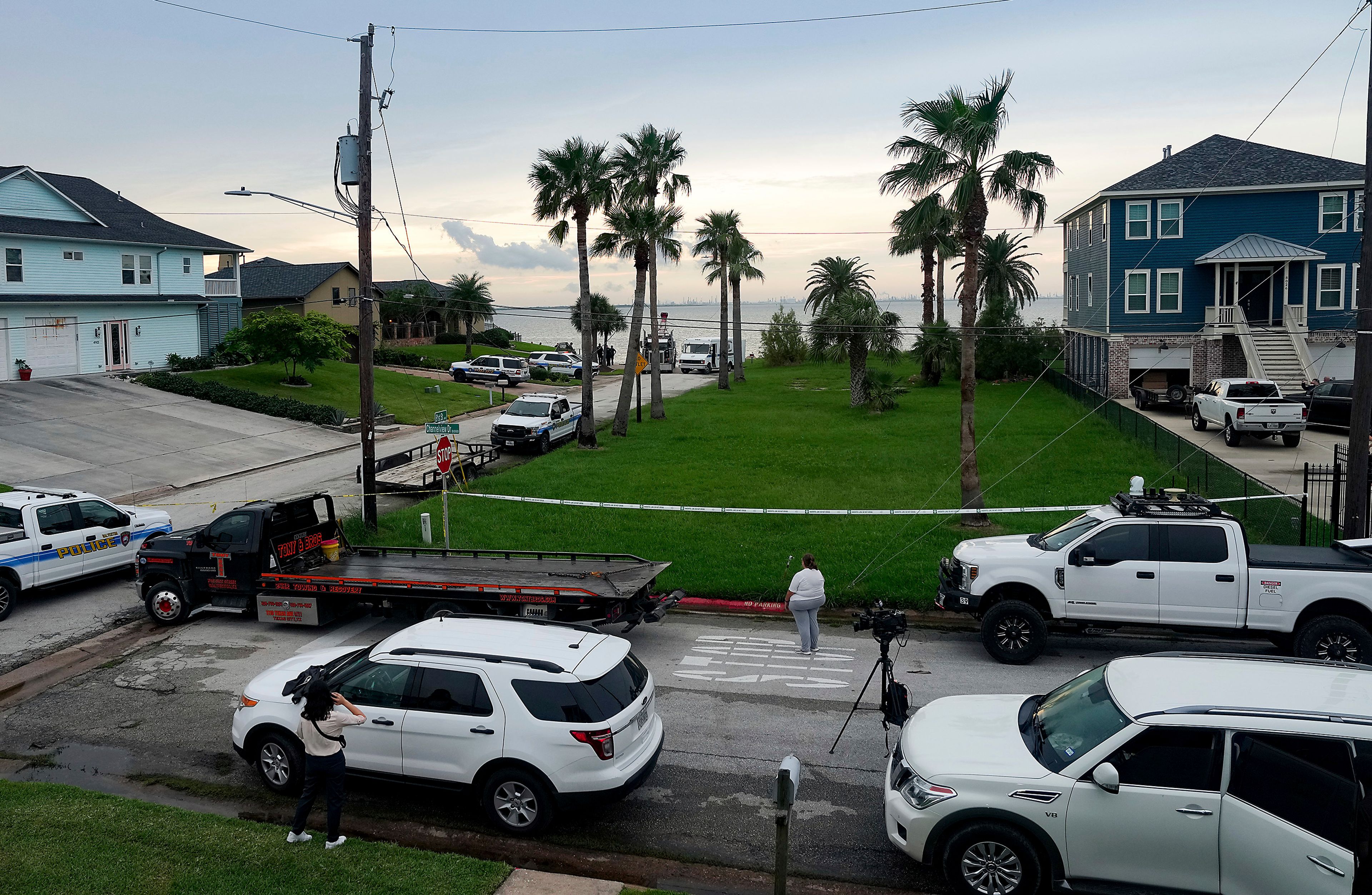 Neighbors and media wait as the Galveston Police Departments pulls a car driven by a suspect in a deadly shooting of Harris County deputy constable Maher Husseini out of the Galveston Ship Channel on the island Tuesday, Sept. 3, 2024 in Galveston, Texas.