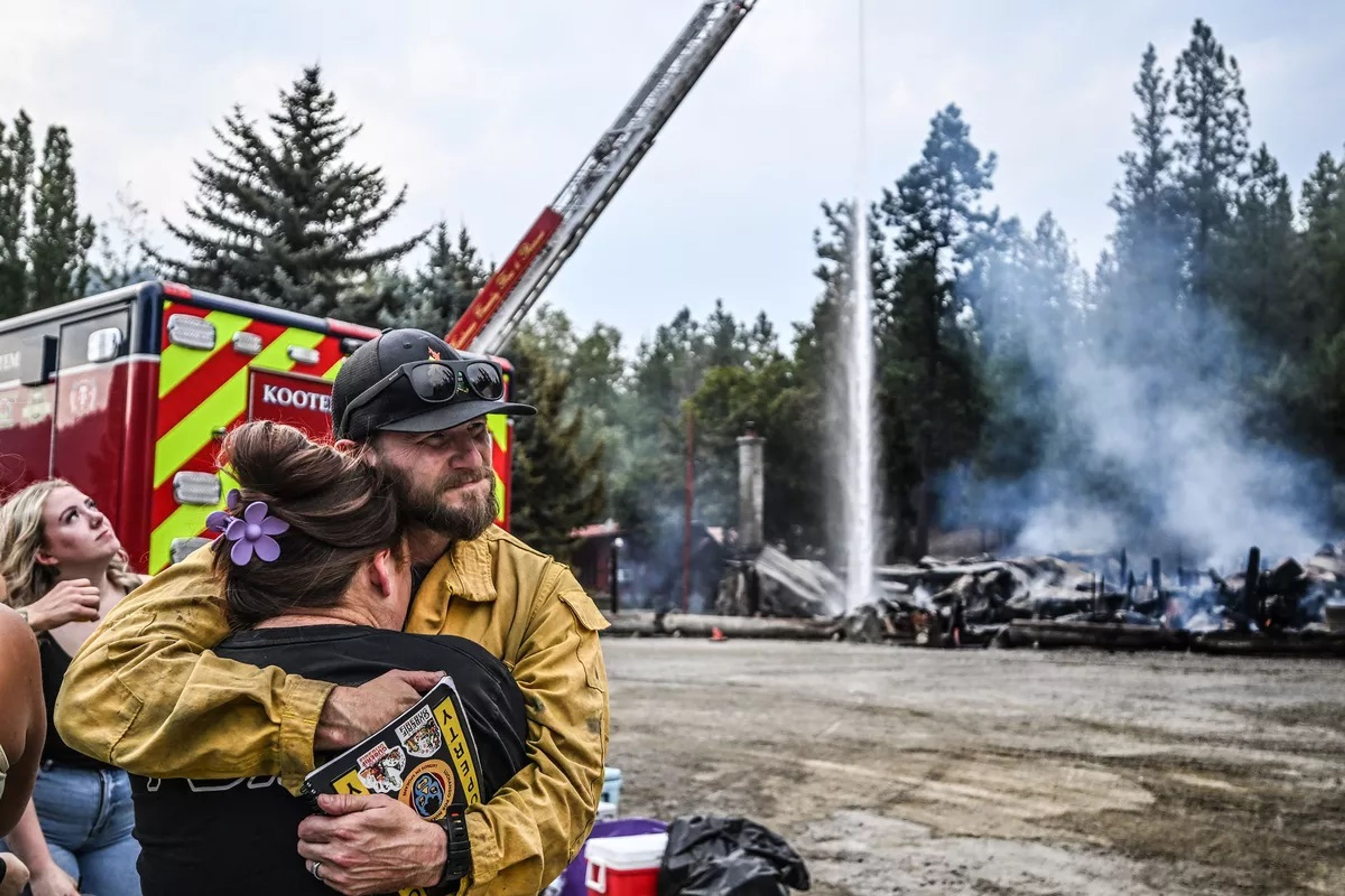 “They put their heart and soul into their jobs here,” says Cody Griffin from Idaho Department of Lands as he hugs waitress Macy Barnes in front of the burned-down Wolf Lodge Inn in Coeur d’Alene on Monday. Macy has worked there for six years. (Kathy Plonka/The Spokesman-Review)