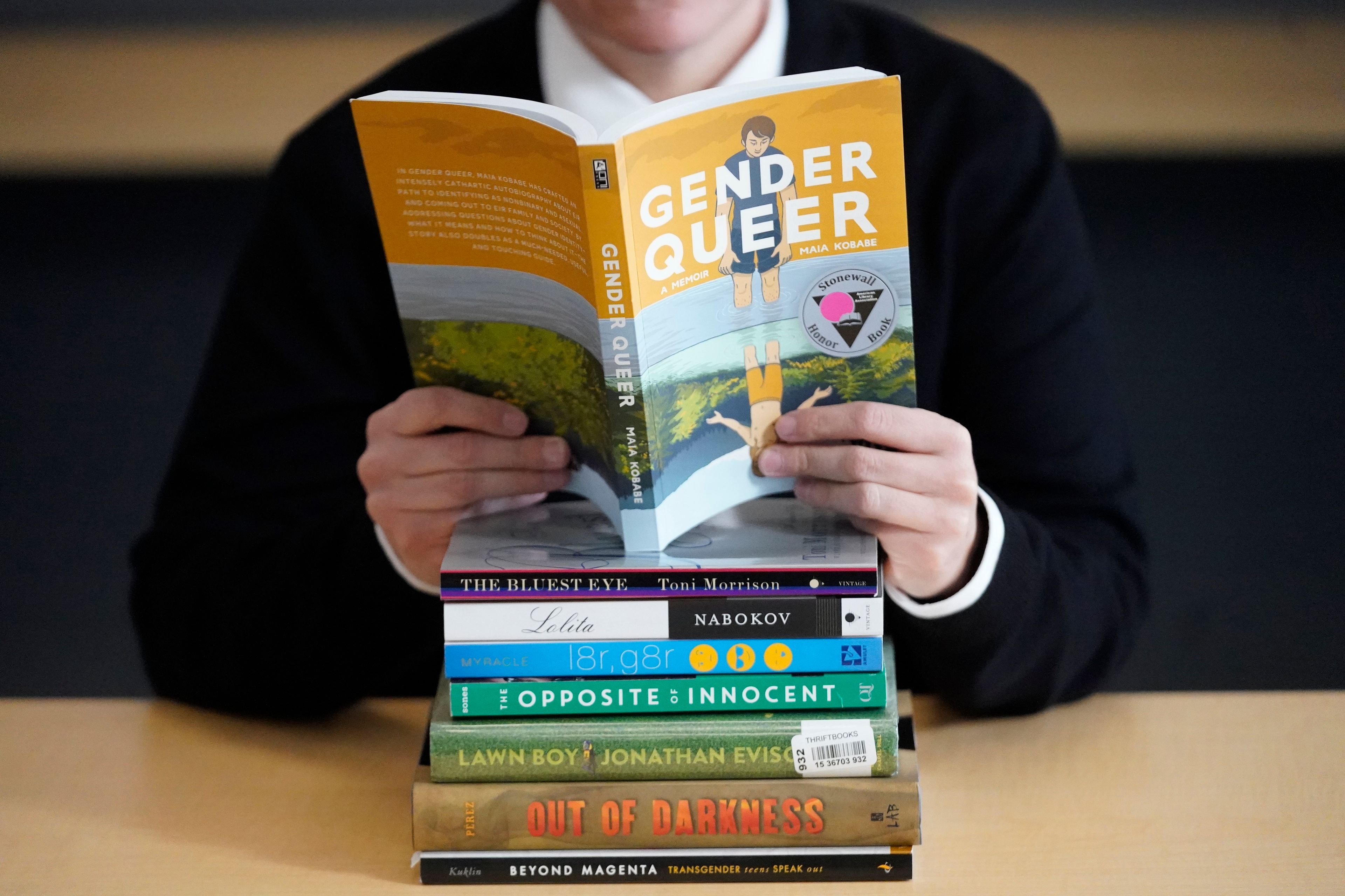 FILE - Amanda Darrow, director of youth, family and education programs at the Utah Pride Center, poses with books that have been the subject of complaints from parents in Salt Lake City on Dec. 16, 2021. The wave of attempted book banning and restrictions continues to intensify, the American Library Association reported Friday. Numbers for 2022 already approach last year's totals, which were the highest in decades. (AP Photo/Rick Bowmer, File)