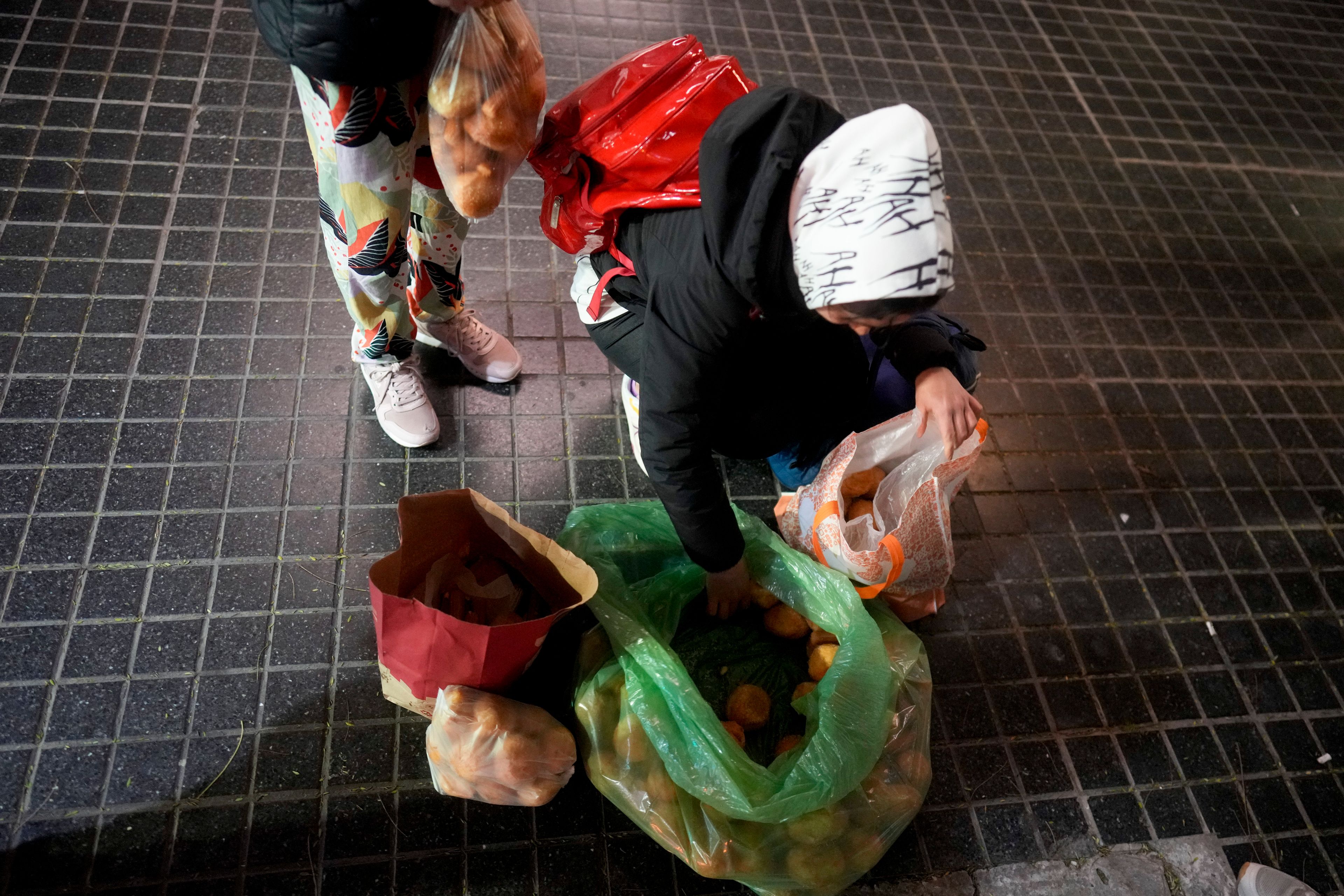 A girl and her mother collect baked goods outside a bakery that gives away what they don't sell by the end of the day, in Buenos Aires, Argentina, Monday, Sept. 9, 2024. (AP Photo/Natacha Pisarenko)