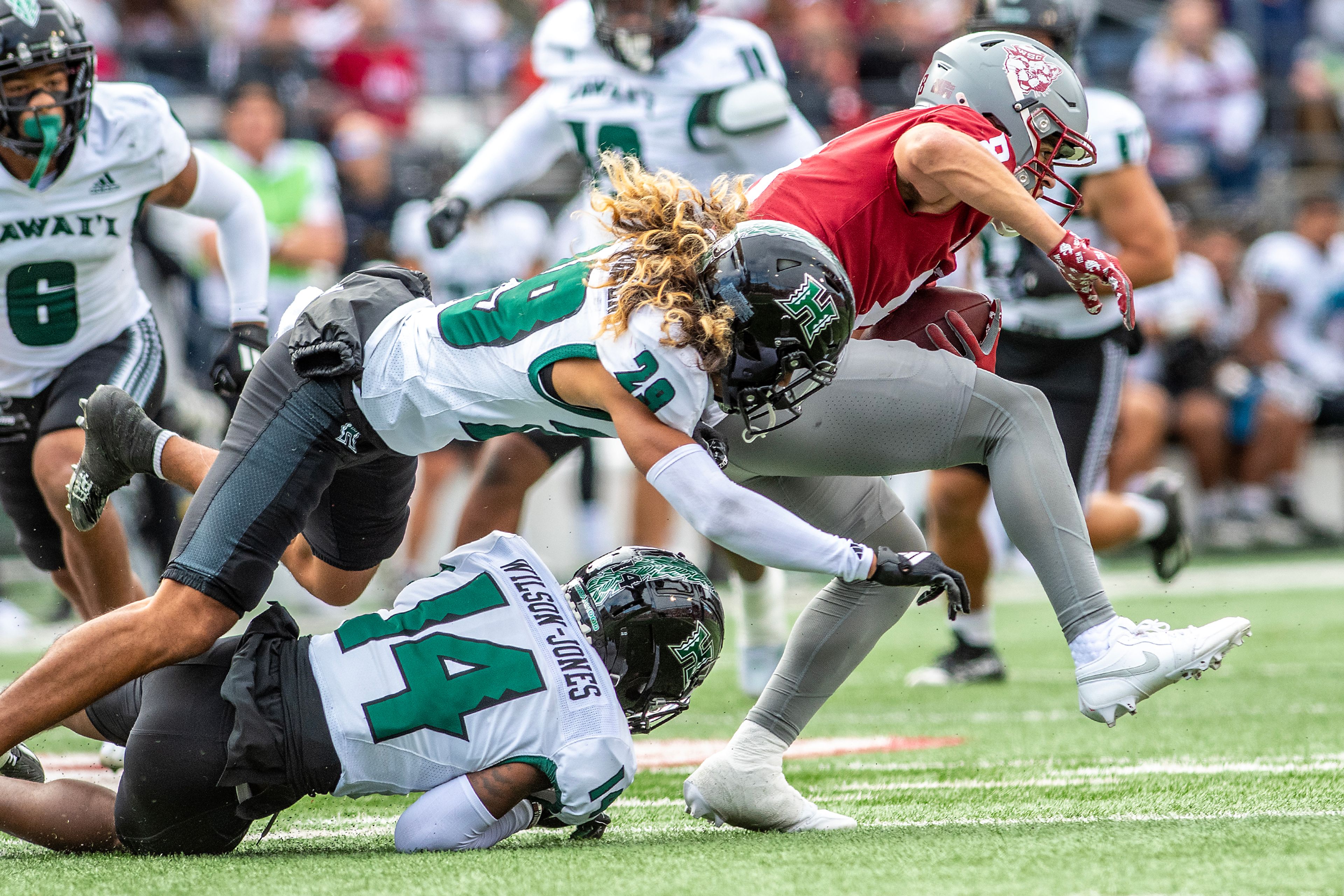 Washington State wide receiver Carlos Hernandez  escapes a tackle from Hawaii defensive back Kilinahe Mendiola-Jensen and defensive back Jaheim Wilson-Jones in a college football game on Saturday at Gesa Field in Pullman.,