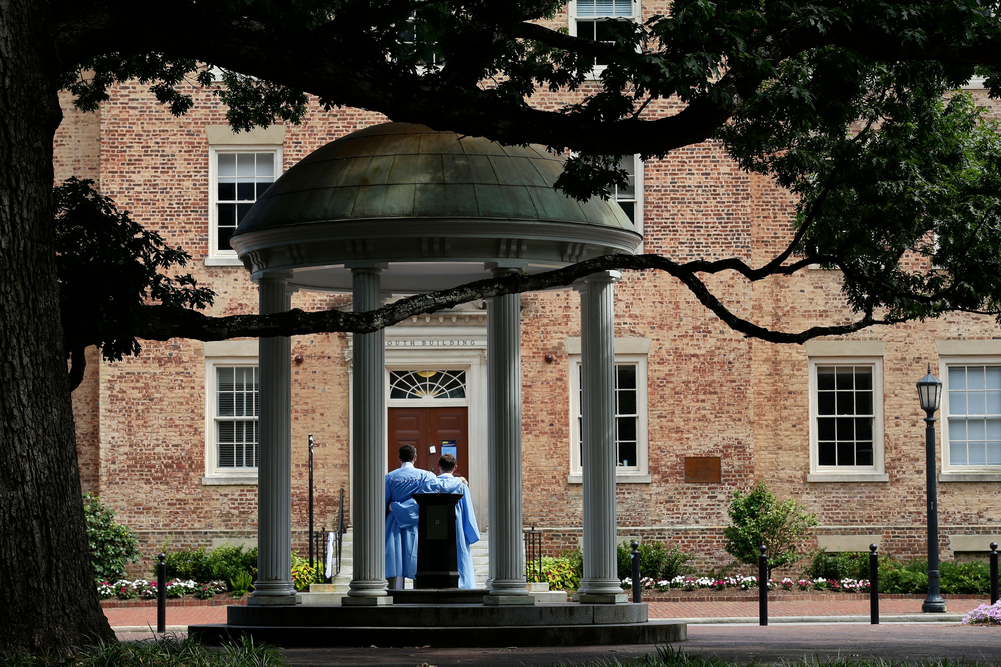 FILE - Graduates of the University of North Carolina take pictures at the Old Well on campus in Chapel Hill, N.C., June 30, 2020.