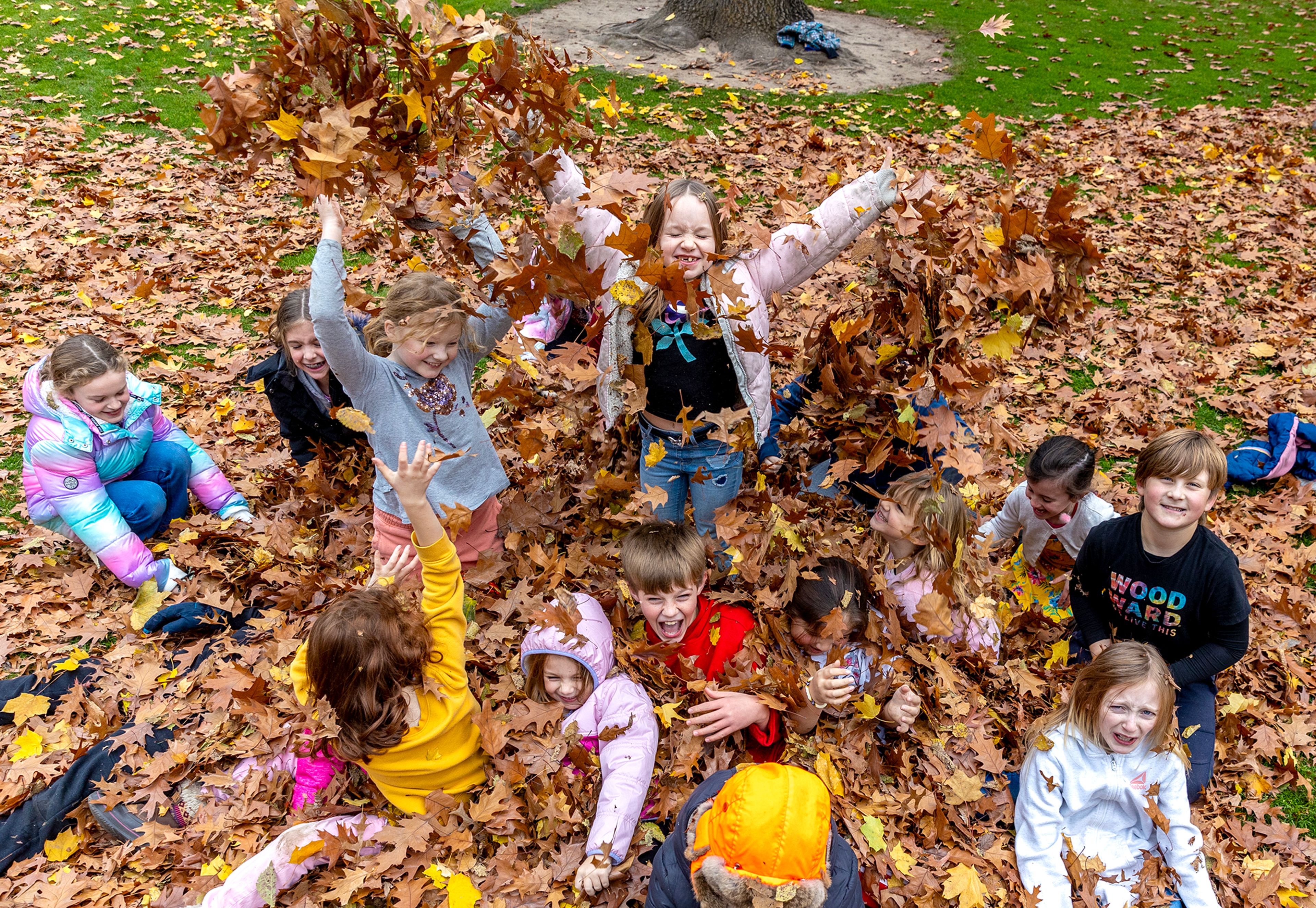 Kids from Children's House Montessori School play in the leaves at Pioneer Park Wednesday in Lewiston.